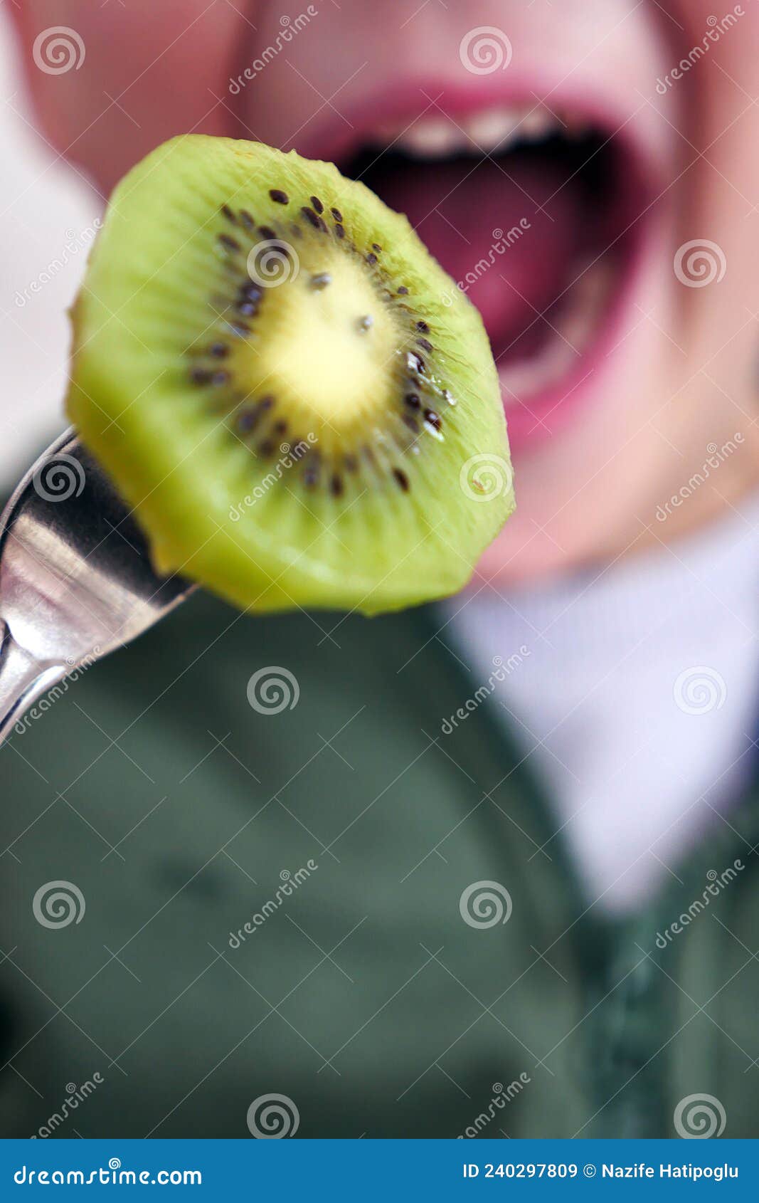 A Child Eating a Kiwi with His Mouth Open, a Slice of Kiwi Fruit Stuck in a Fork Stock Image