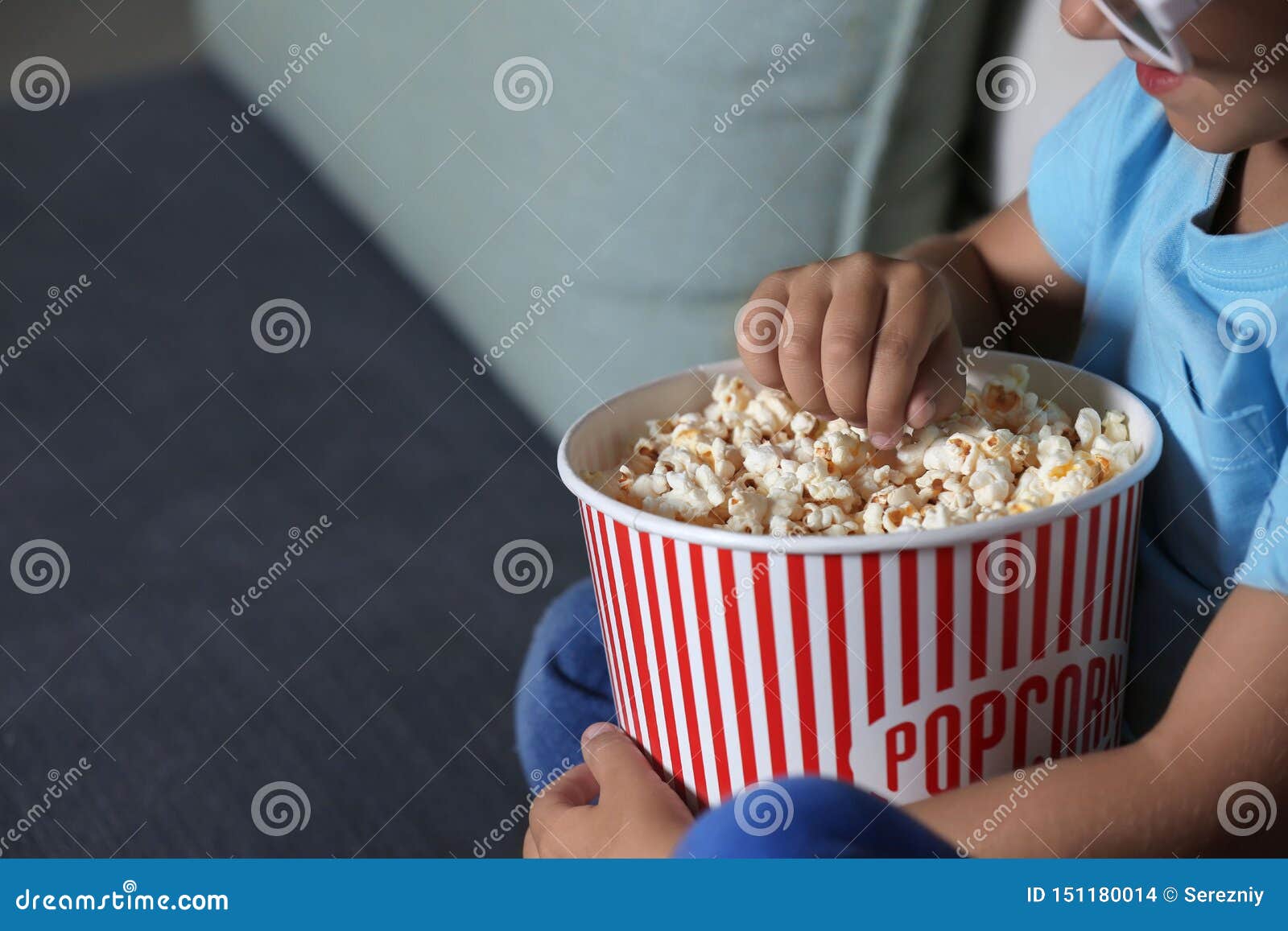 Child Eating Popcorn while Watching TV in Evening, Closeup Stock Photo