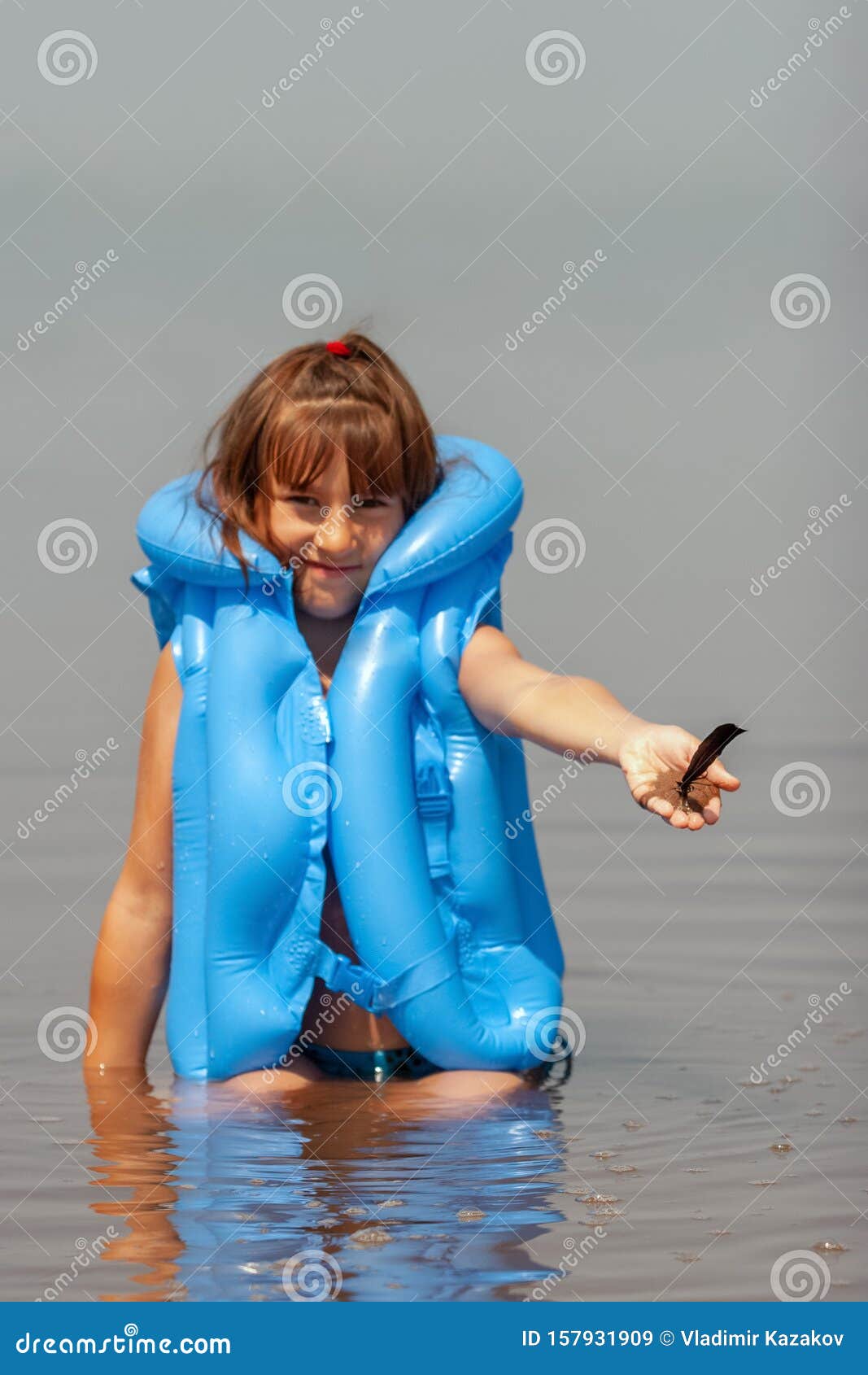 Child Girl in a Blue Inflatable Life Jacket Smiling Sits Playing in the ...