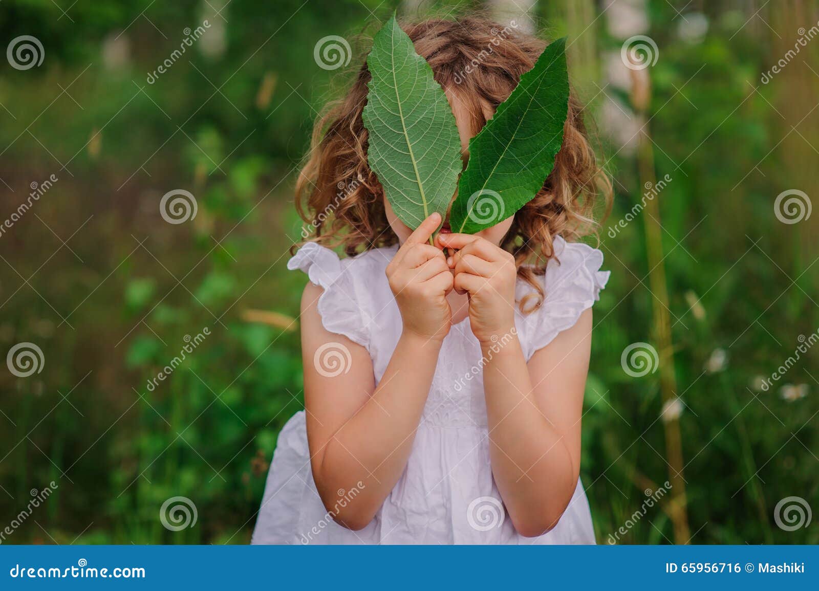 child girl playing with leaves in summer forest with birch trees. nature exploration with kids.