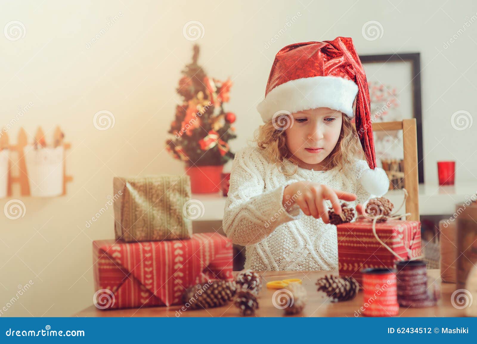 child girl preparing gifts for christmas at home, cozy holiday interior