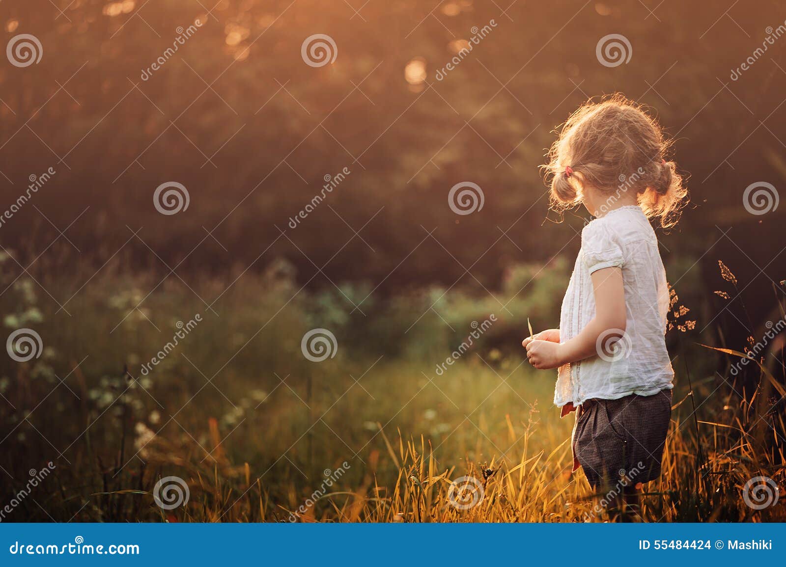 child girl in white shirt on the walk on summer sunset field