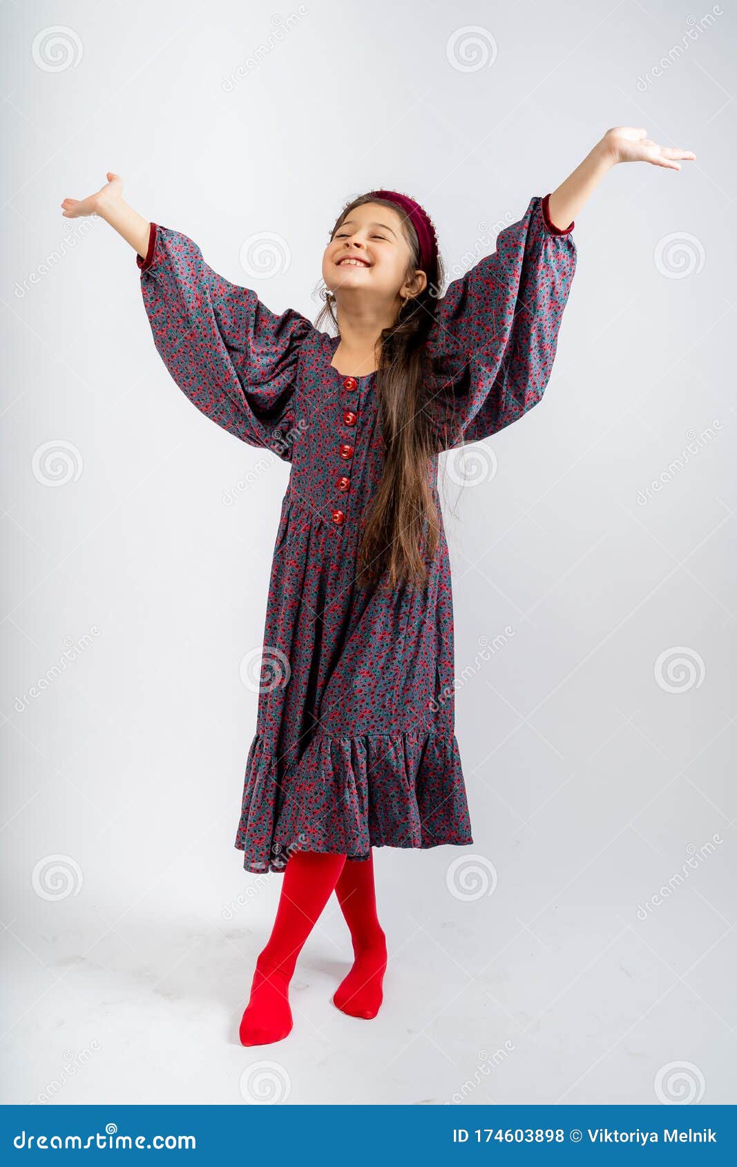 a child in a gray dress with flowers, with red buttons, in red tights,  on a white background.