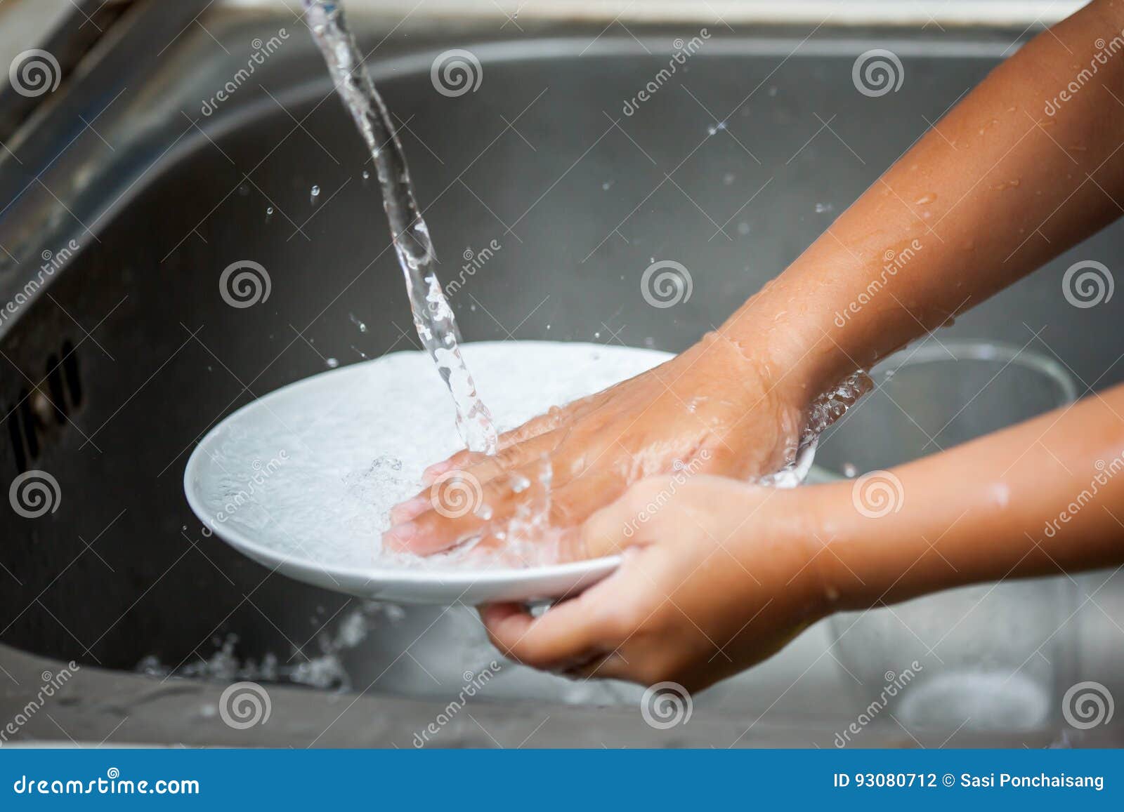 child hand washing dishes over the sink