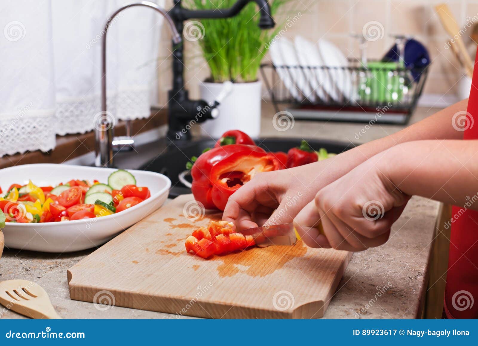 child hands chopping a red bellpepper for a fresh vegetables sal