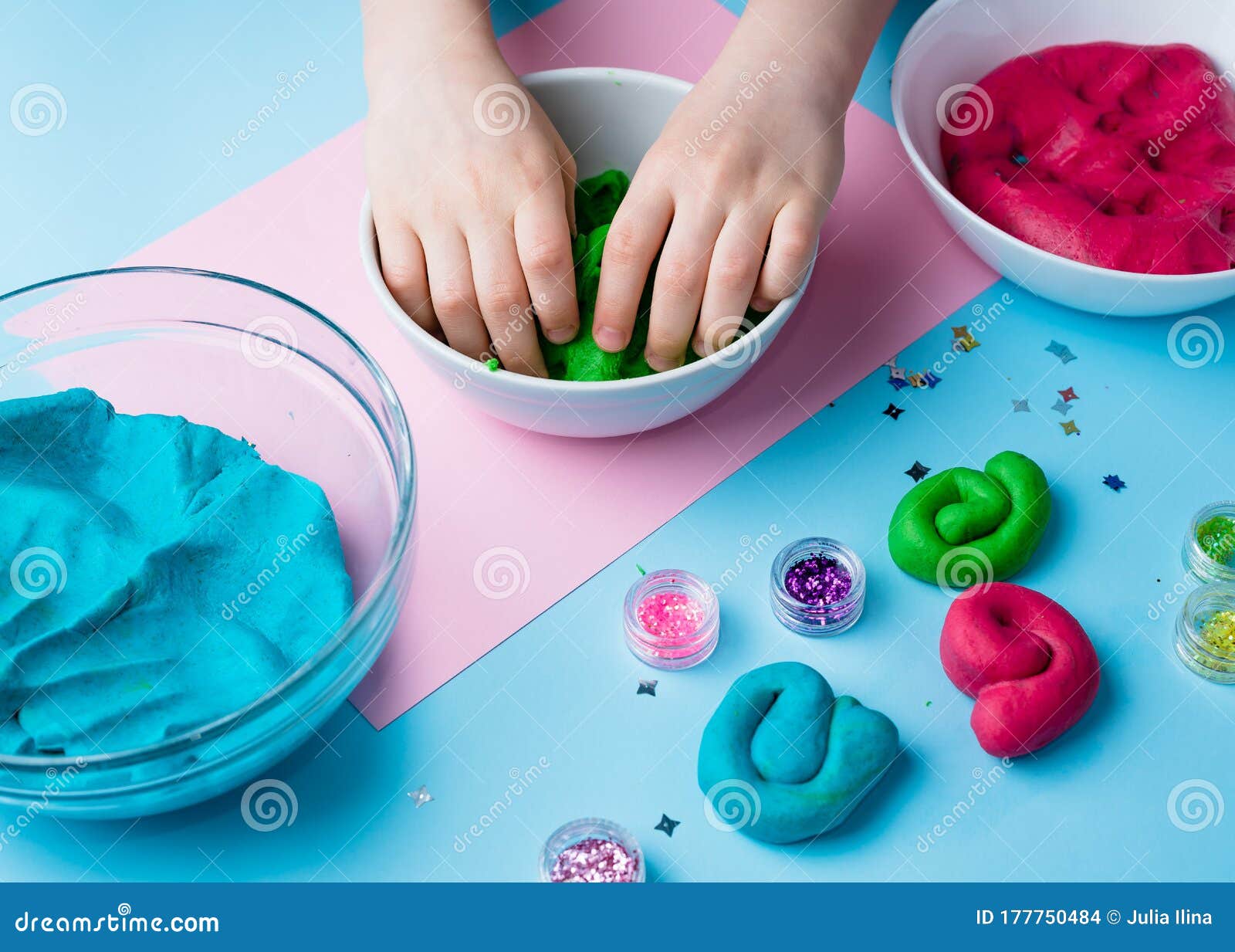 Child hands playing with colorful clay. Homemade plastiline. Plasticine.  play dough. Girl molding modeling clay. Homemade clay. Stock Photo