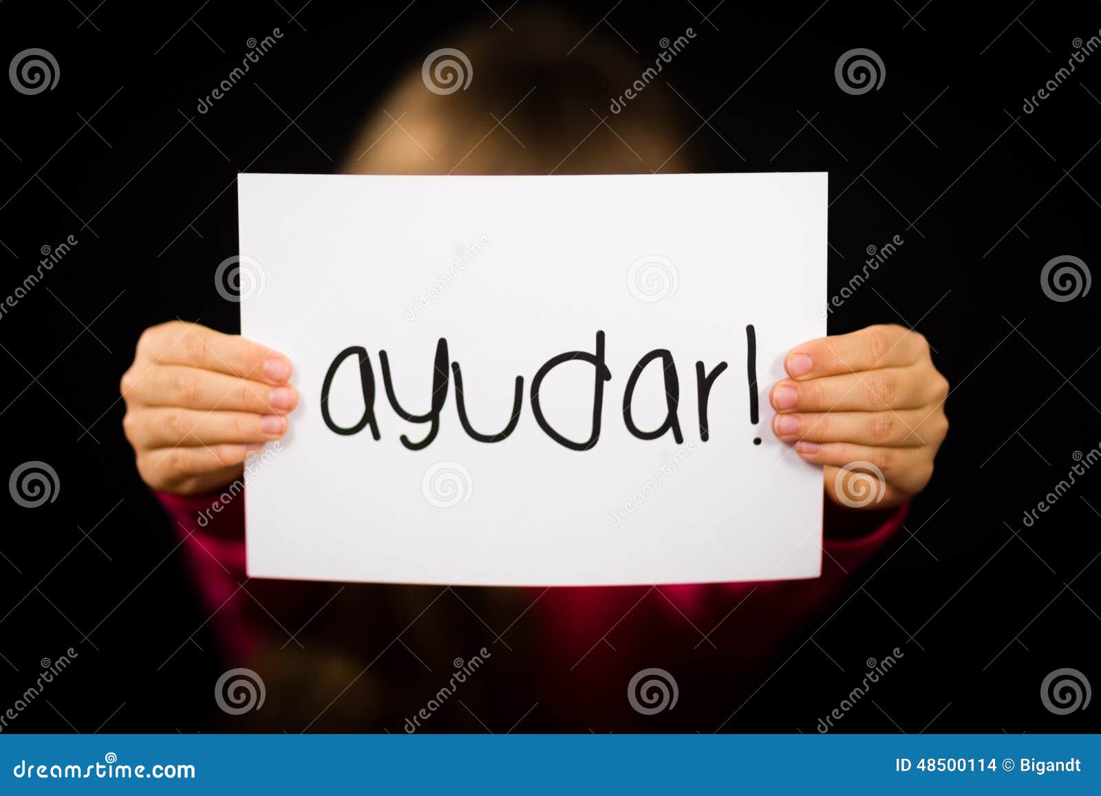 child holding sign with spanish word ayudar - help