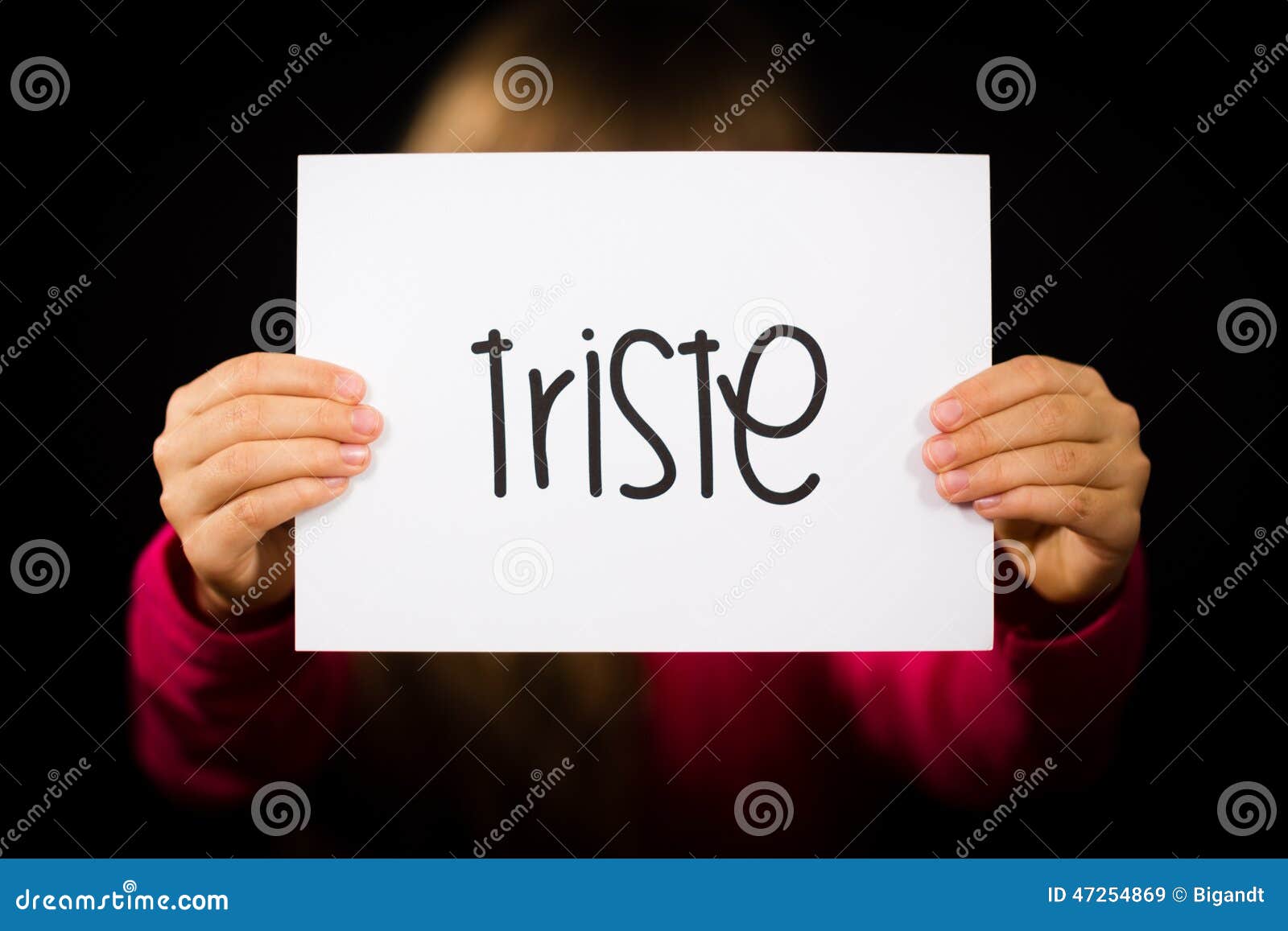 child holding sign with spanish word triste - sorry