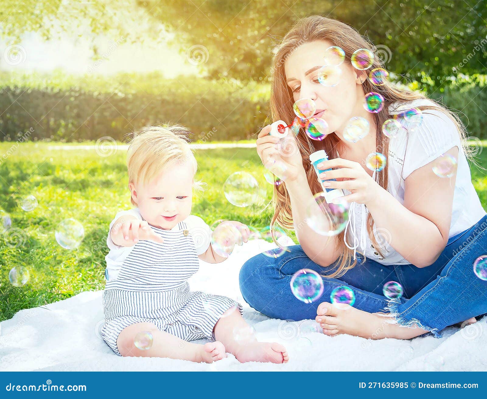 child (kid) having fun with mother and soap bubbles in a sunny summer day. caucasians happy baby (boy).