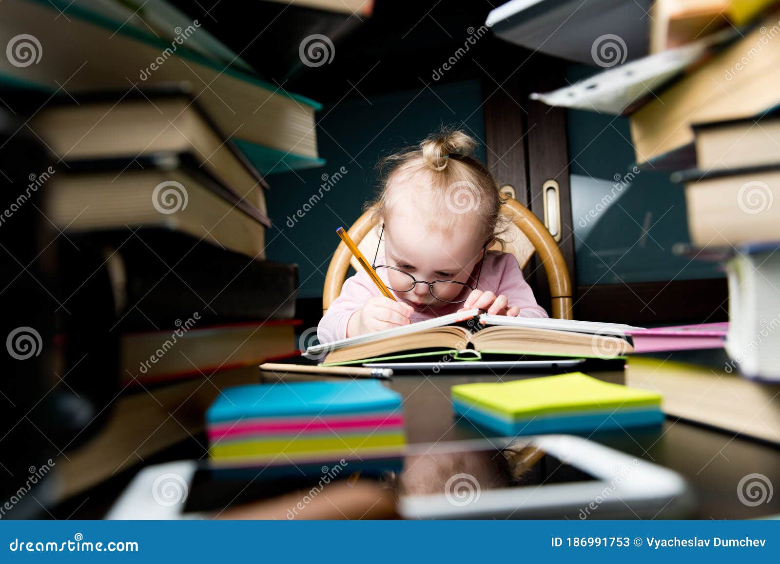 a child in large glasses painstakingly writes something in a notebook