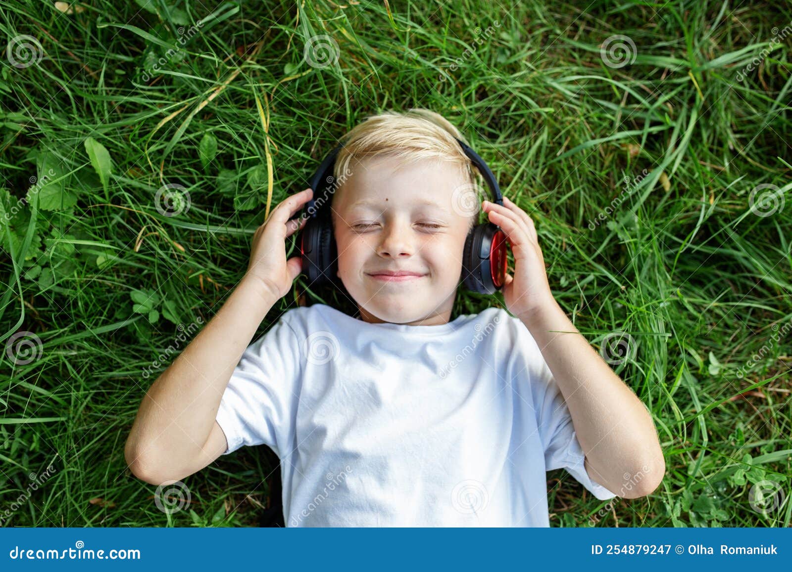 Child Listens To Music Blond Boy Uses Headphones And Smart Phone Lies child-listens-to-music-blond-boy-uses-headphones-and-smart-phone-lies