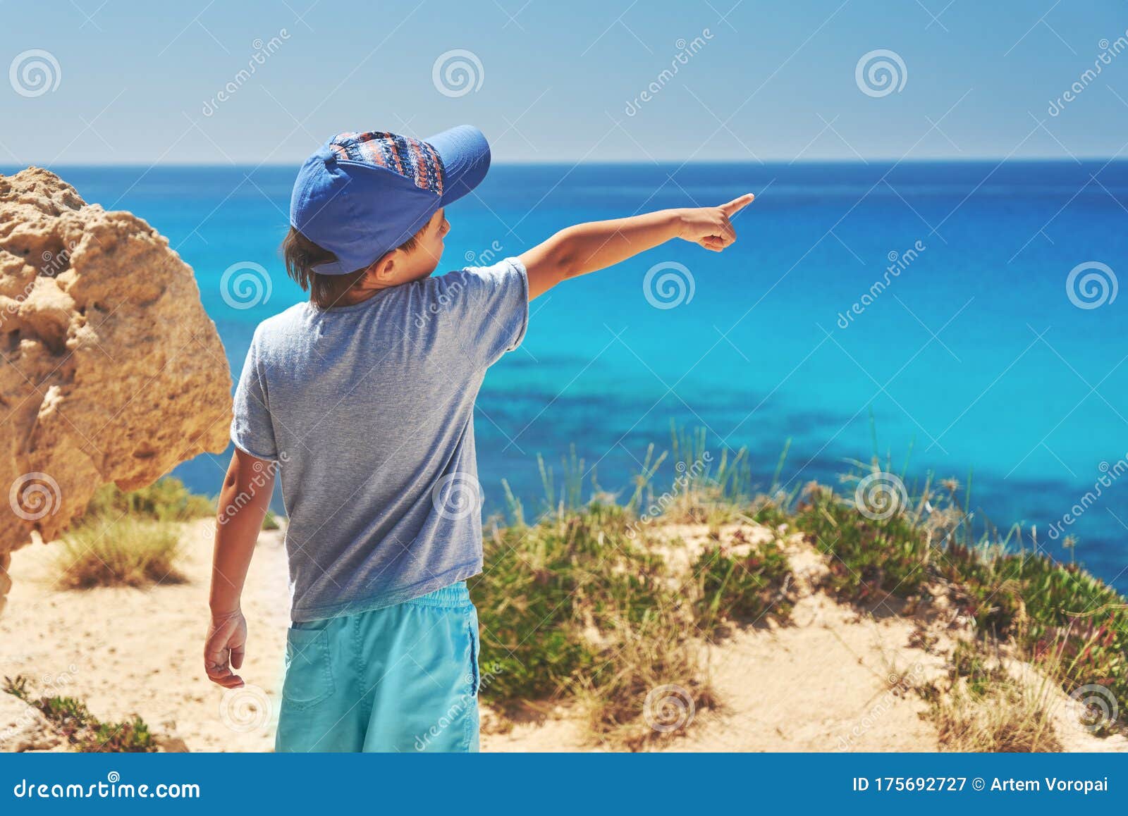 child is looking to the sea being on the picturesque cliffy coast.
