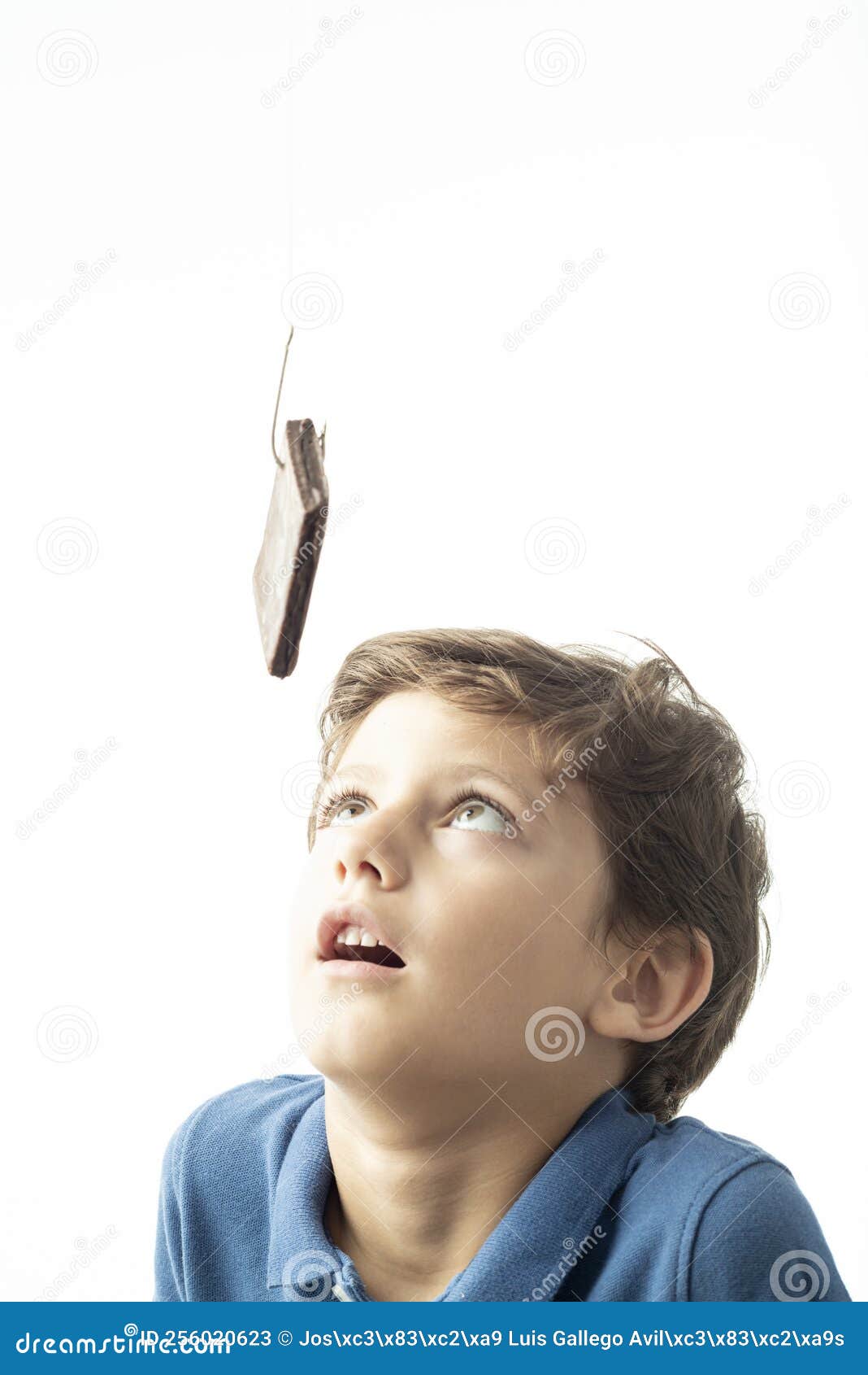 a child looks longingly at a sponge cake hanging from a hook