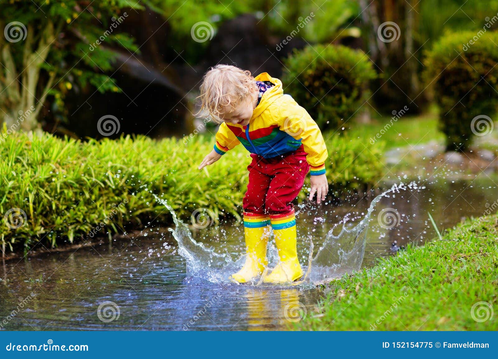 child playing in puddle. kids jump in autumn rain