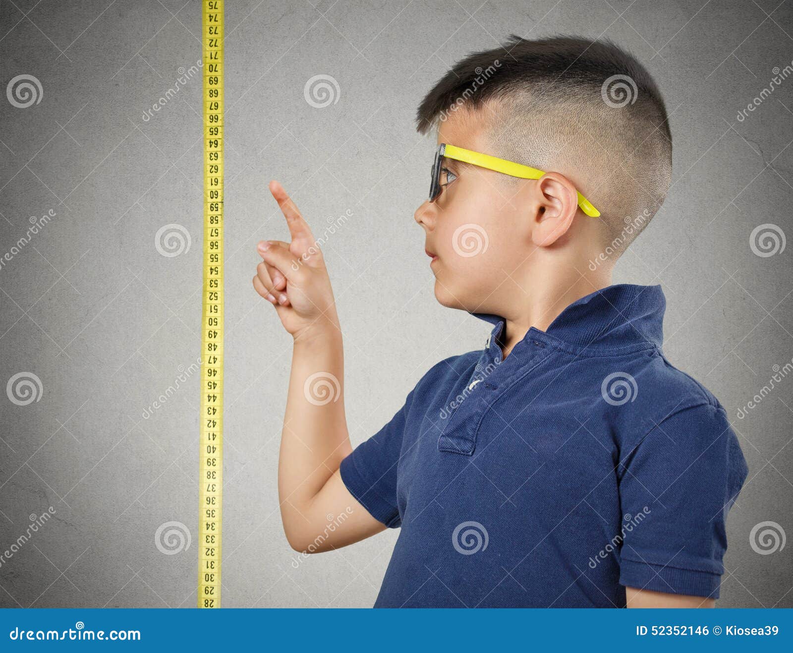 child pointing at his height on measuring tape