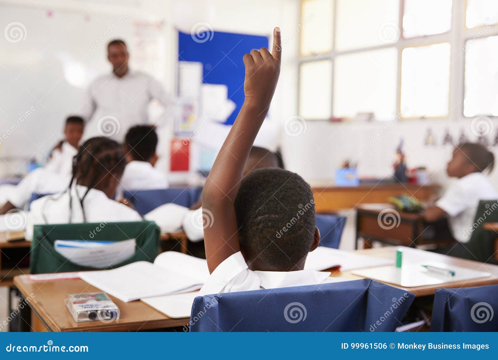 child raising hand to answer in an ary school lesson