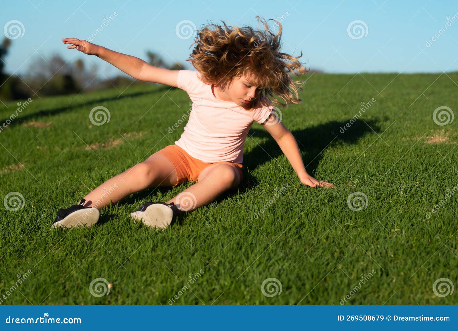 Child Running Tripped And Falls Down. Kid Runs Through The Spring Grass Child Running Tripped And Falls Down. Kid Runs Through The Spring Grass