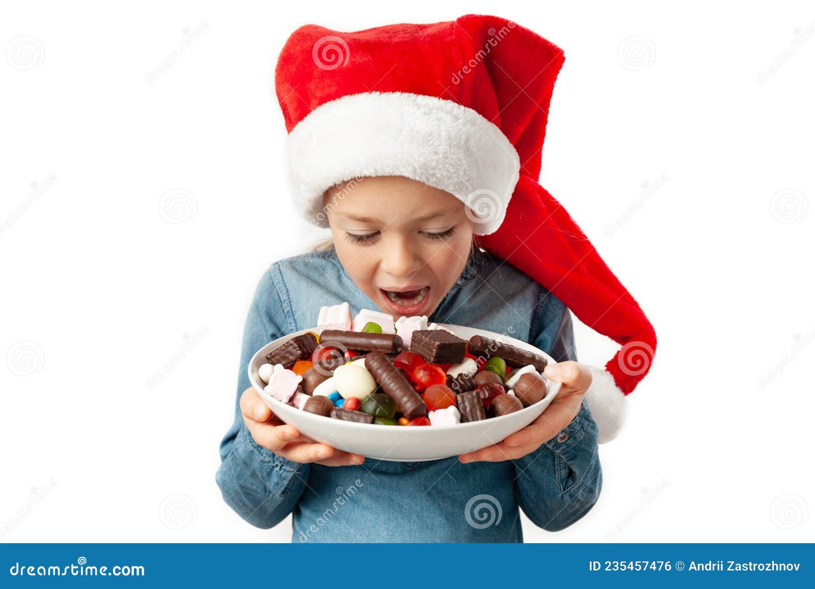 a child in a santa hat adores sweets. a plate full of assorted chocolates in the hands of a little girl