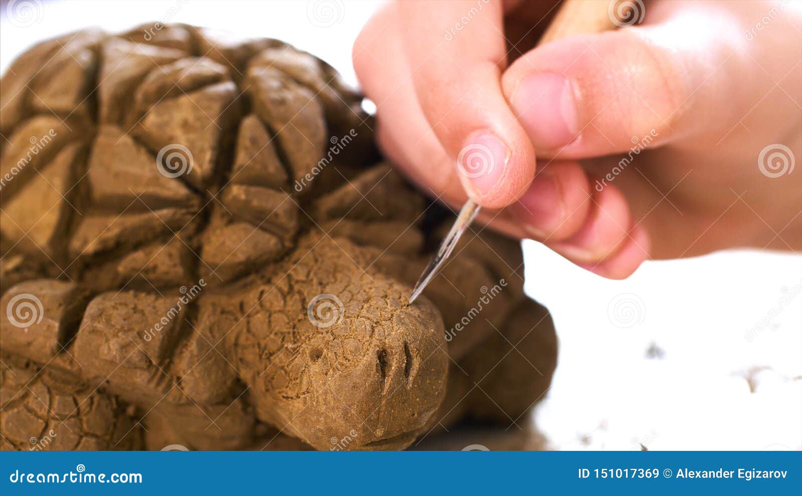 child is scratching the texture of the scales on handmade turtle toy from clay