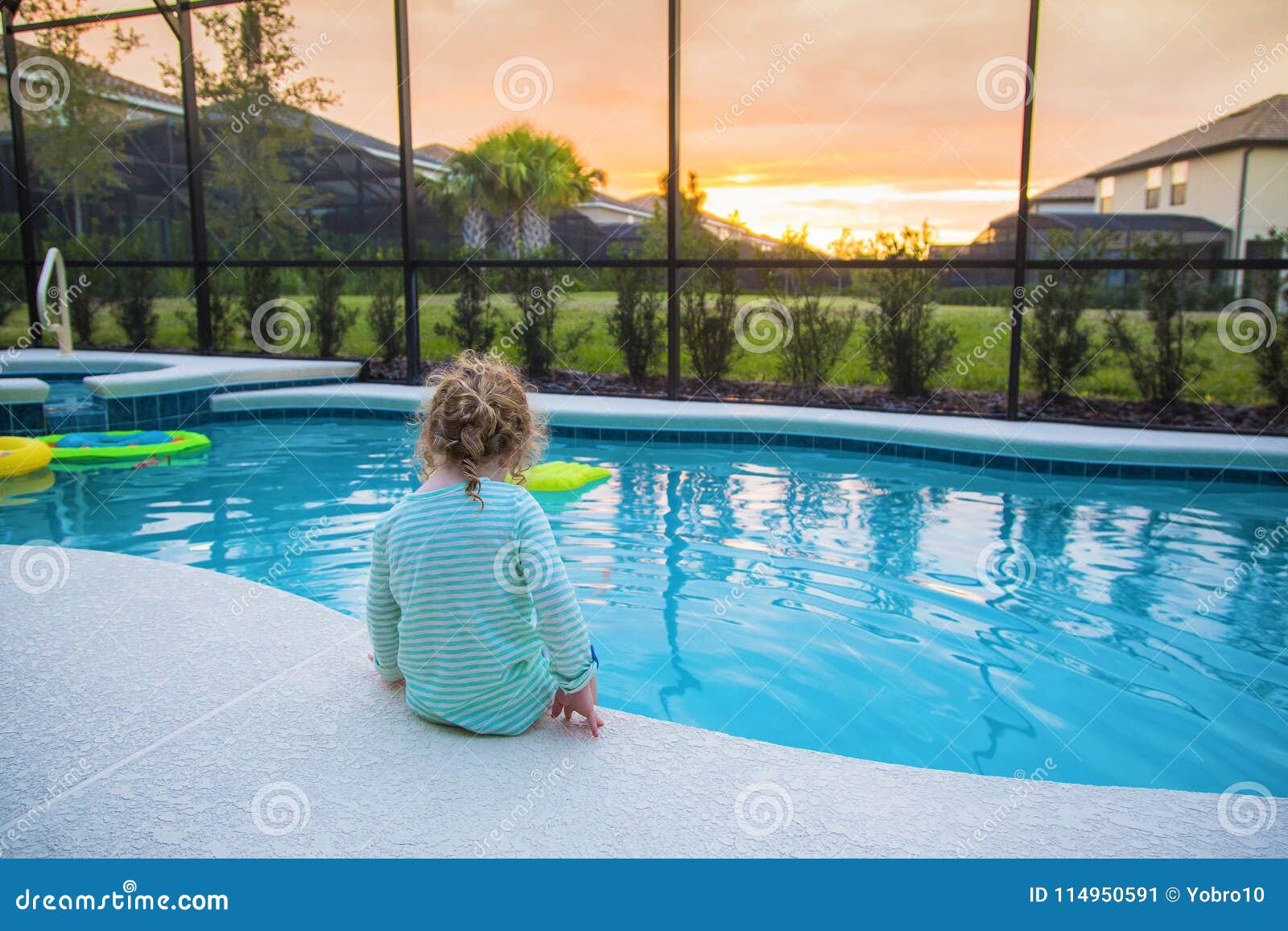 child sitting on the edge of a swimming pool on a warm summer day