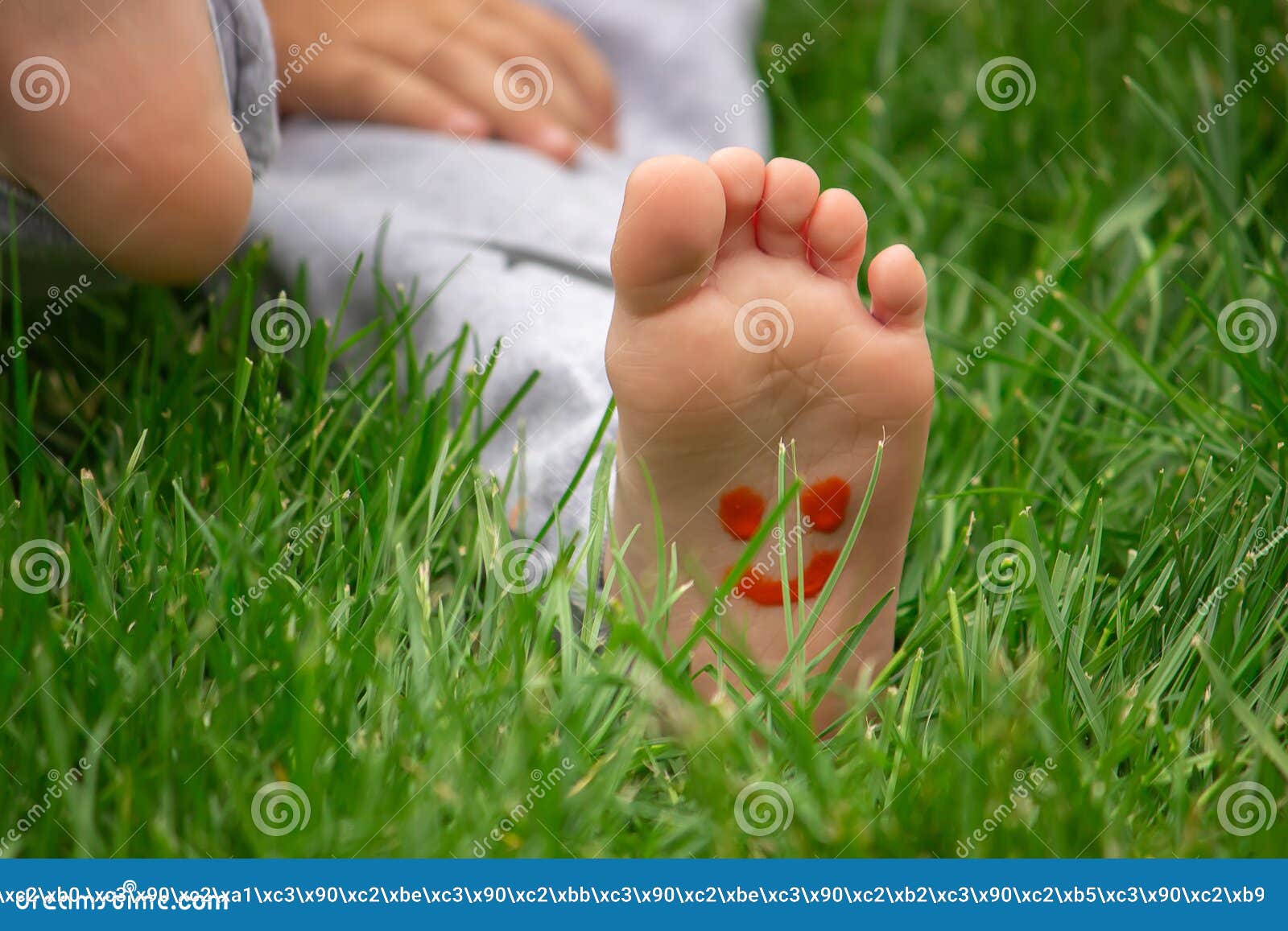 Child Sitting On The Grass Smiling On The Childand X27s Leg With Paints
