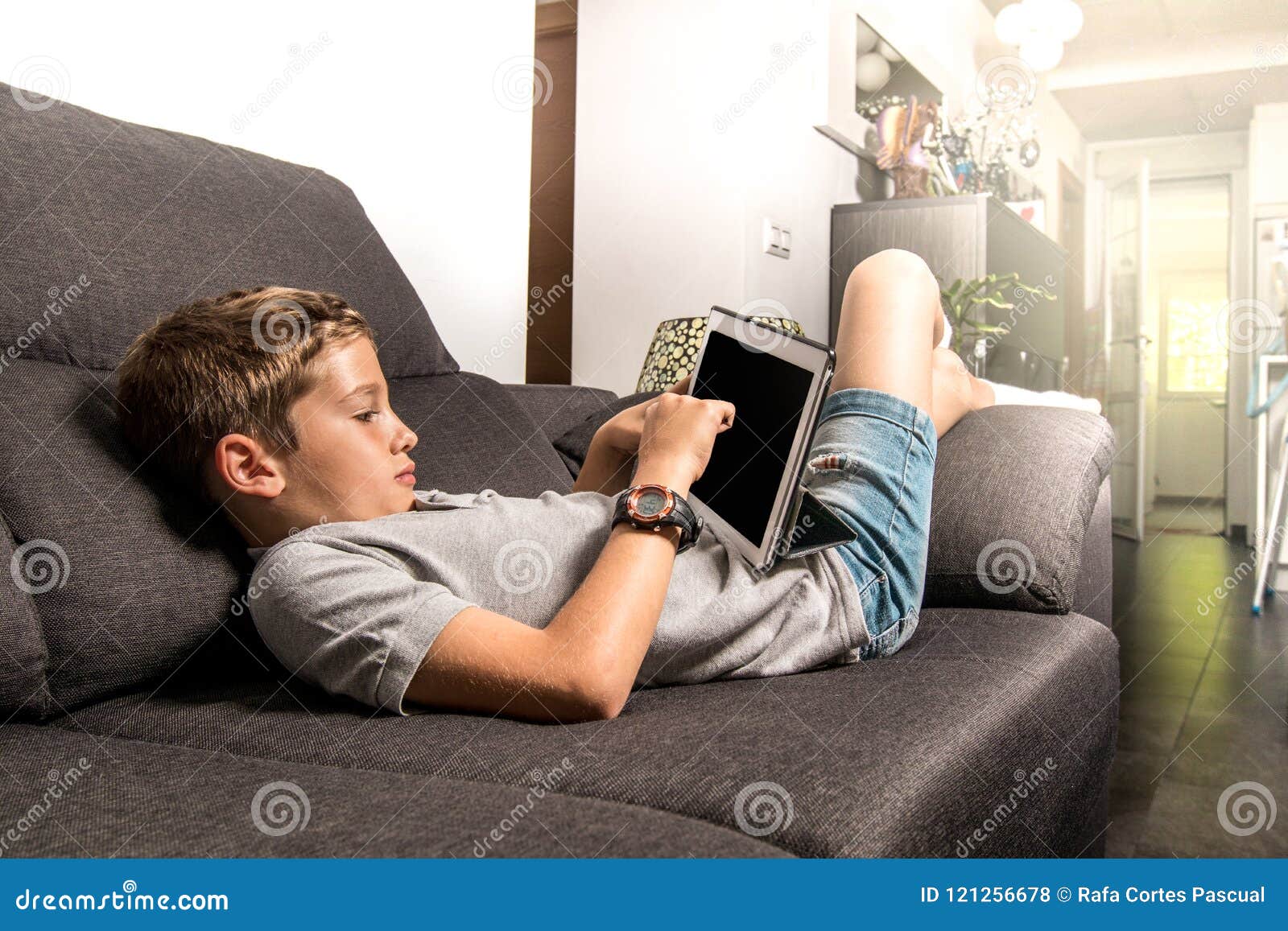Banzai computadora multitud Child on the Sofa at Home Looking at a Tablet Stock Photo - Image of  leisure, child: 121256678