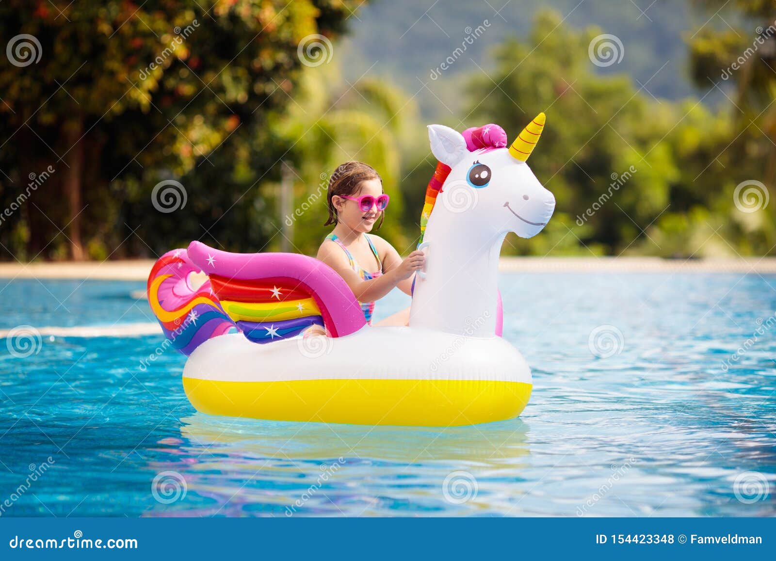 child on unicorn float in swimming pool. kids swim