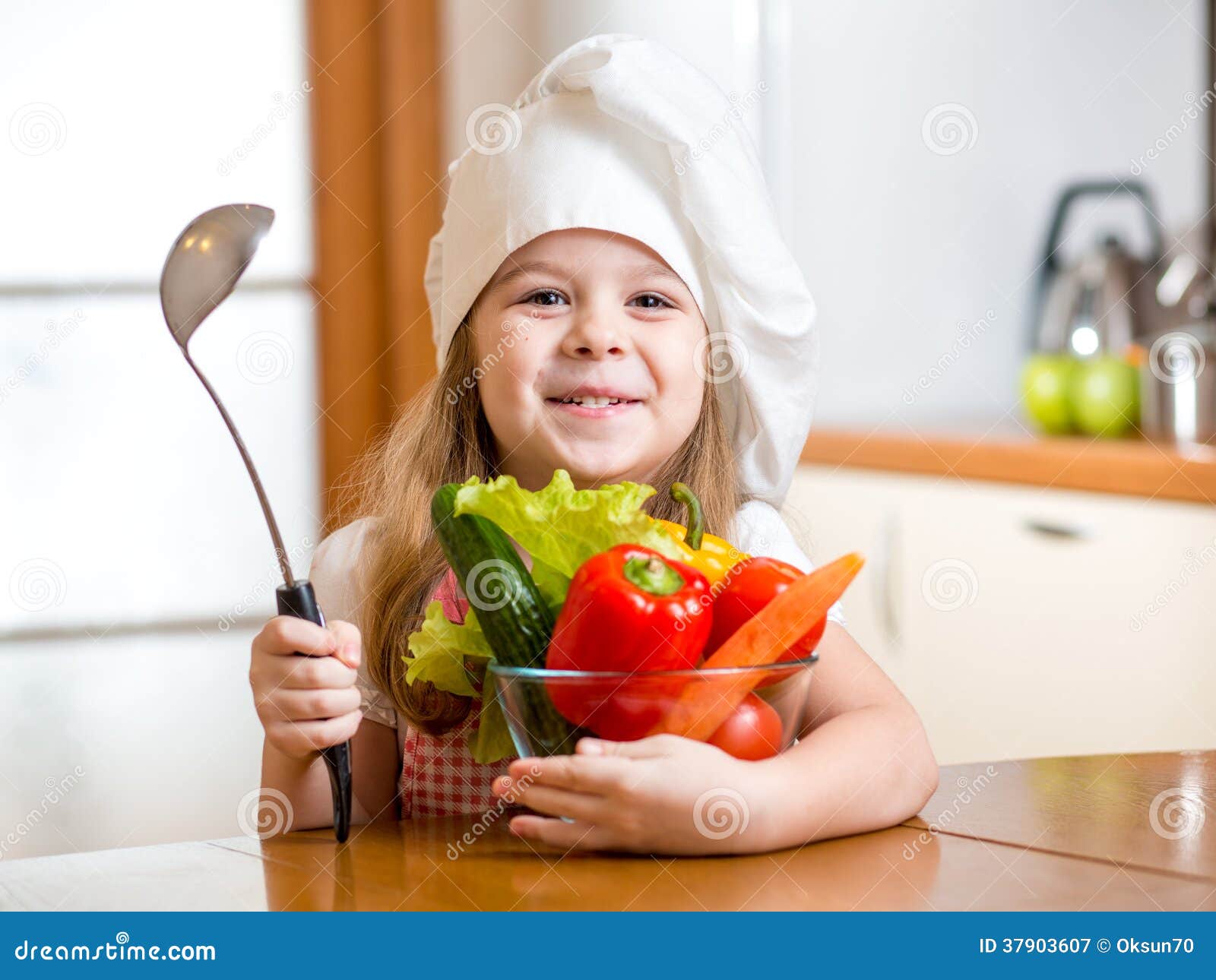 child weared as cook with vegetables at kitchen