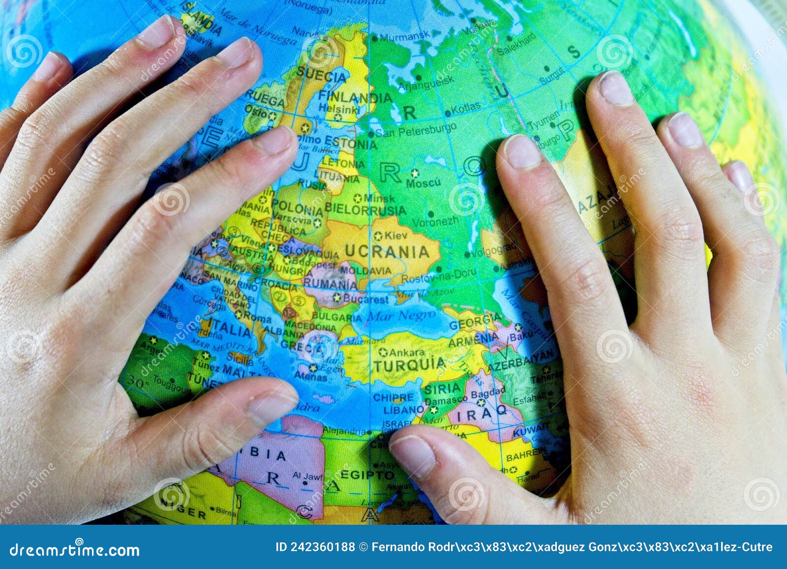 child& x27;s hand on a globe circling ukraine in spanish & x27;ucrania& x27;