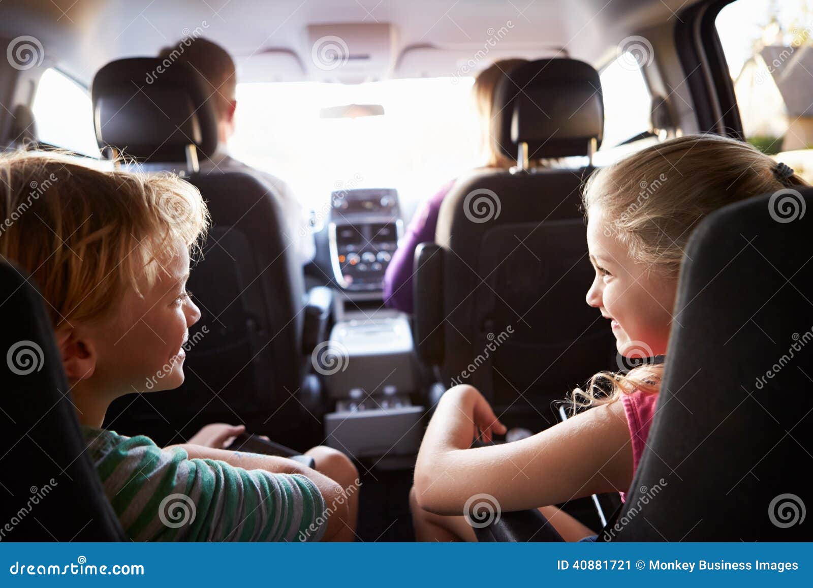 children in back seat of car on journey with parents