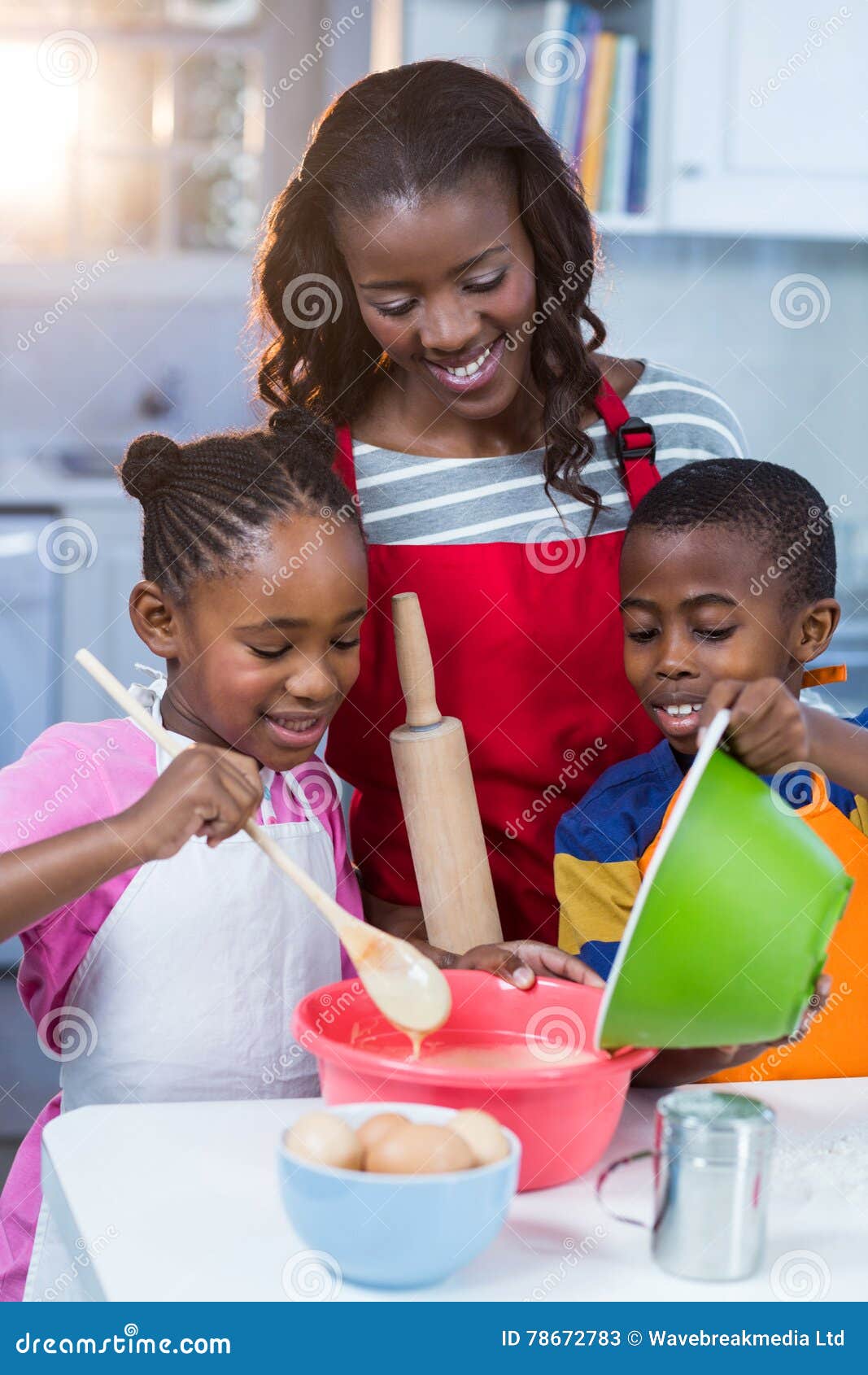 Children preparing cake with their mother in kitchen