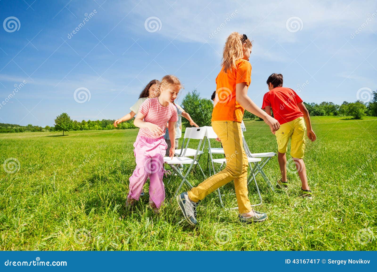 children run around chairs playing game outside summer period 43167417