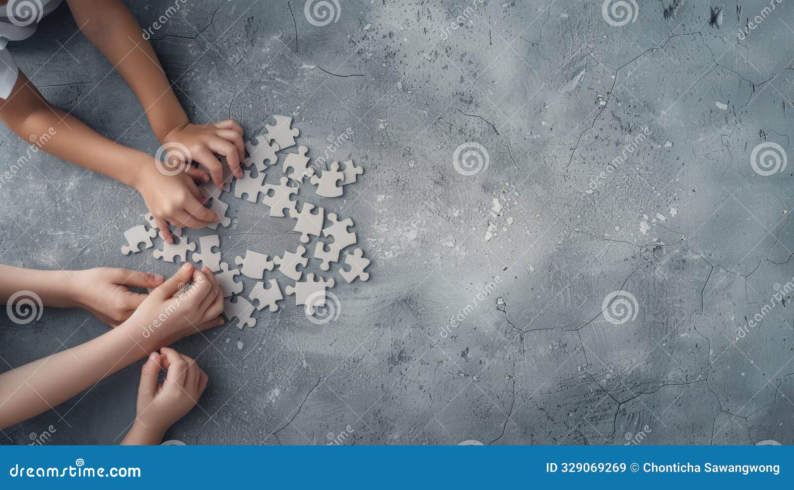 children's hands working together on a puzzle on a gray textured table. collaboration, teamwork, and problem-solving concept