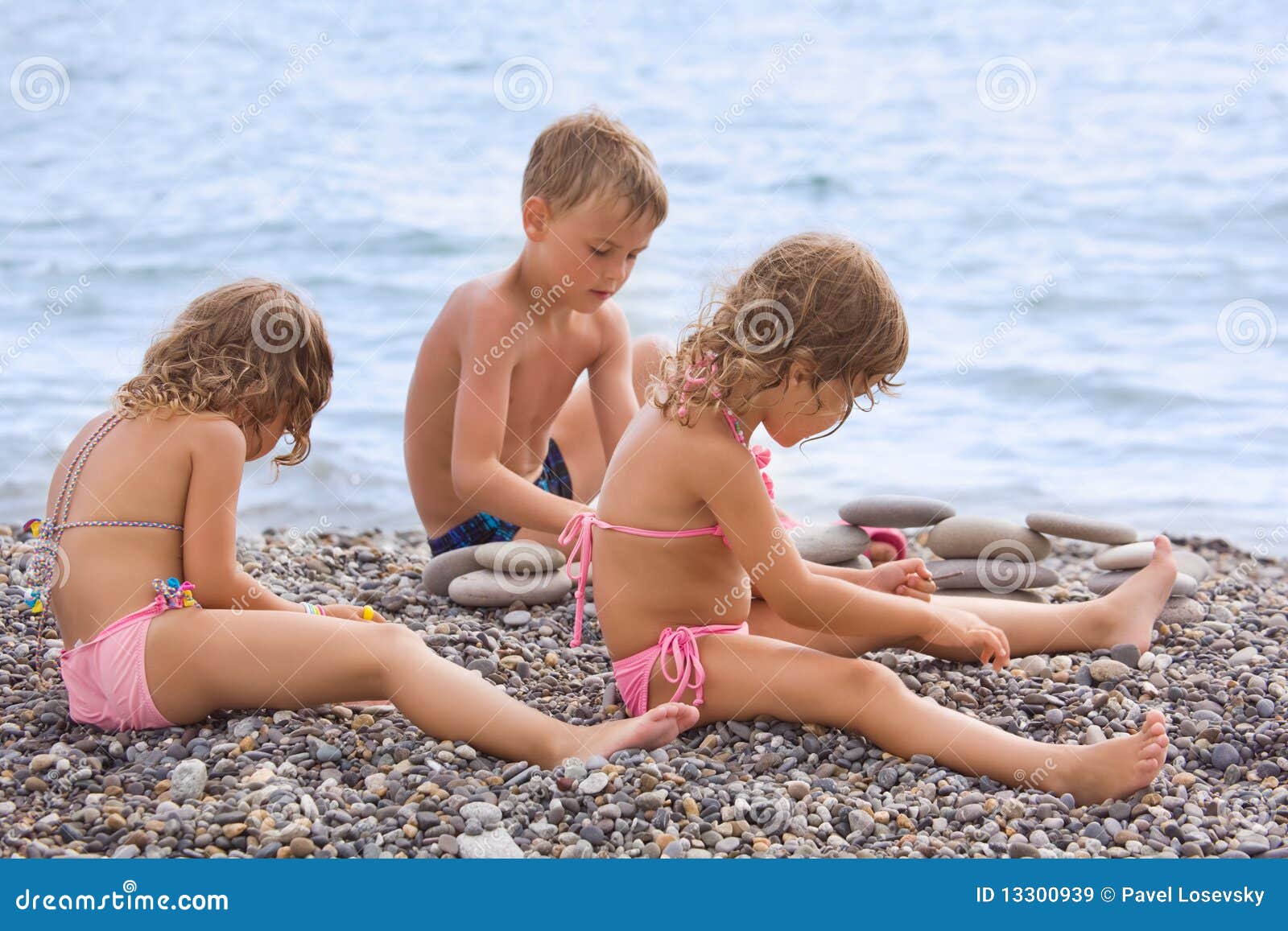children sitting on stony beach, creates pyramid