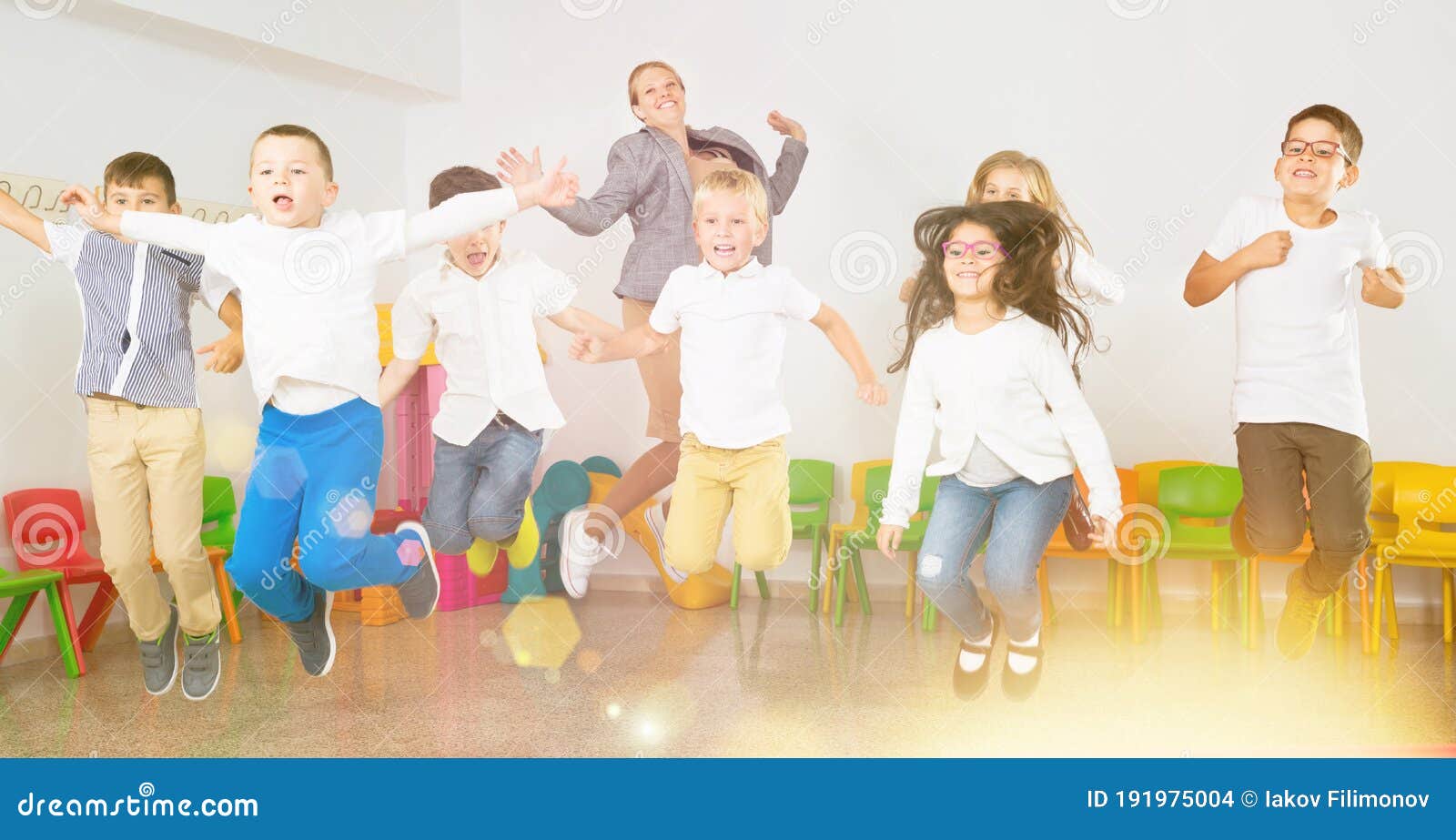 children with teacher jumping together in schoolroom
