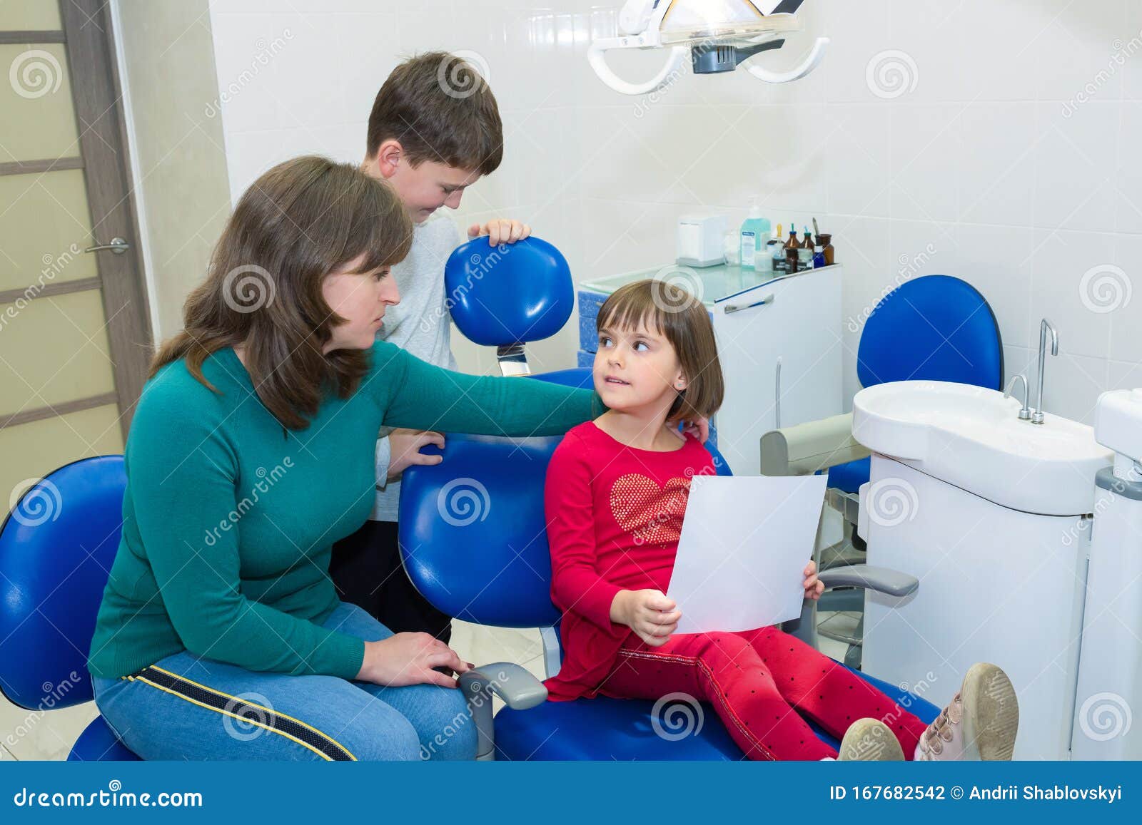 children with their mother are looking at a dental x-ray in a dentistÃ¢â¬â¢s clinic