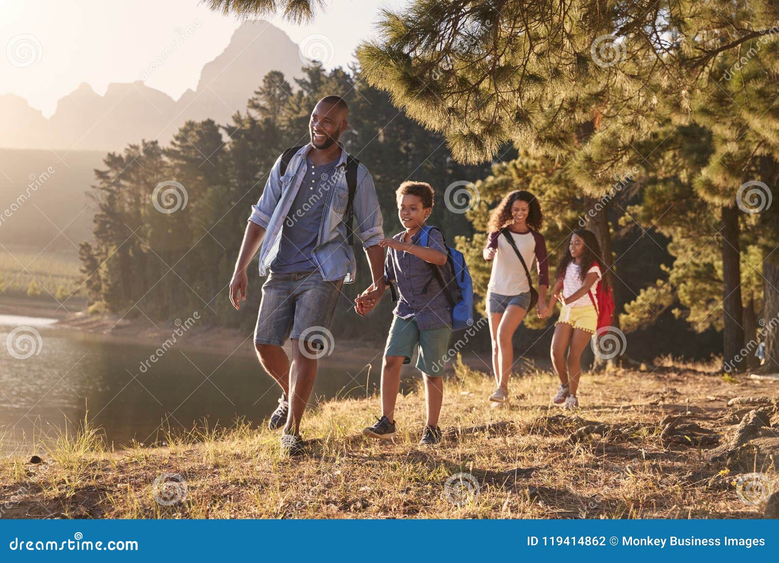 children walk by lake with parents on family hiking adventure
