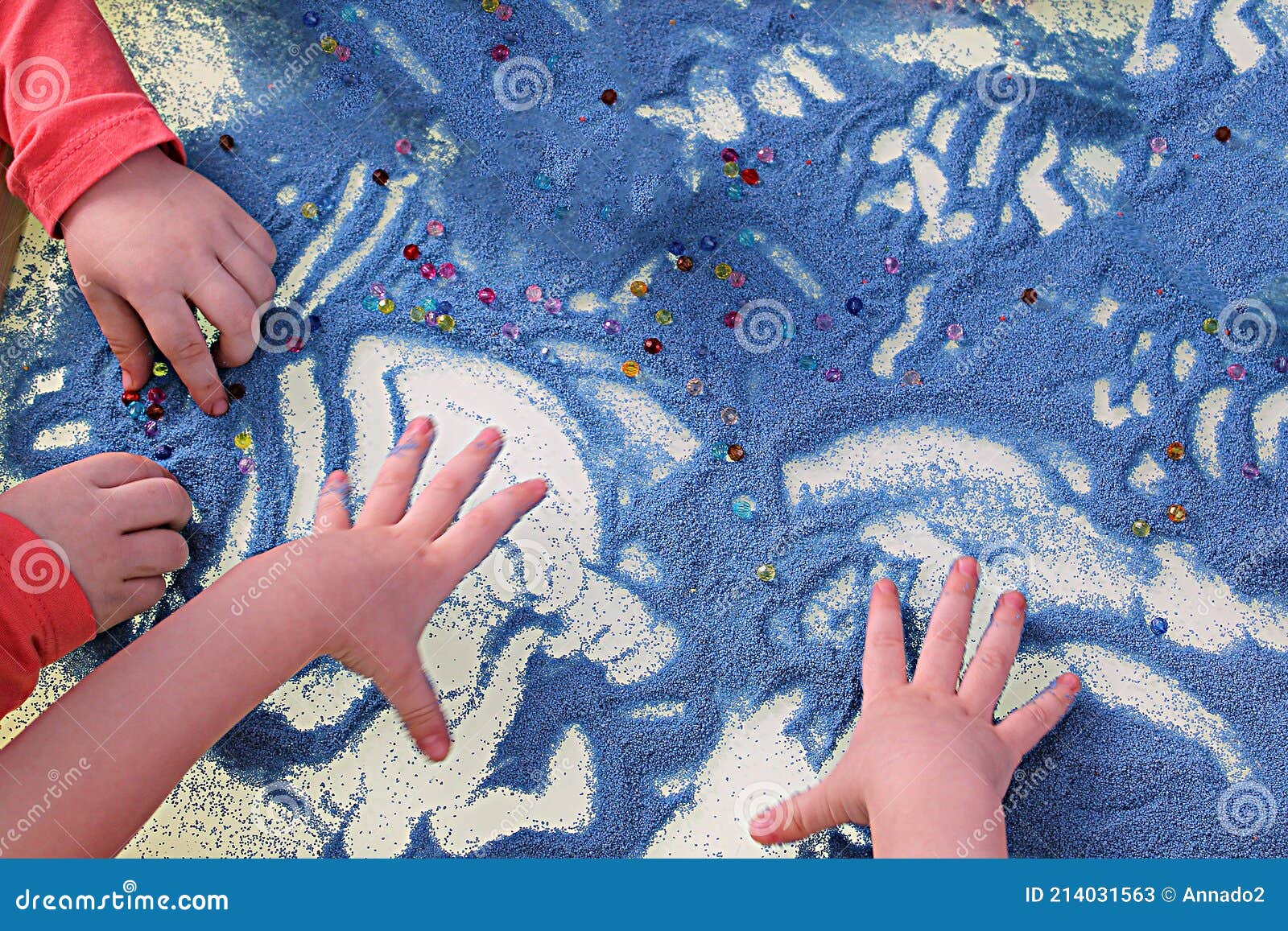 childrens hands touching blue sand on white table sand therapy, development of fine motor skills