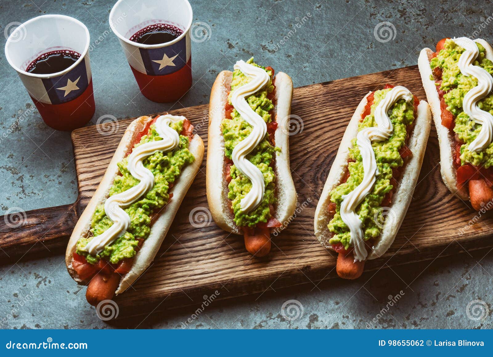 chilean completo italiano. hot dog sandwiches with tomato, avocado and mayonnaise served on wooden board with drink in