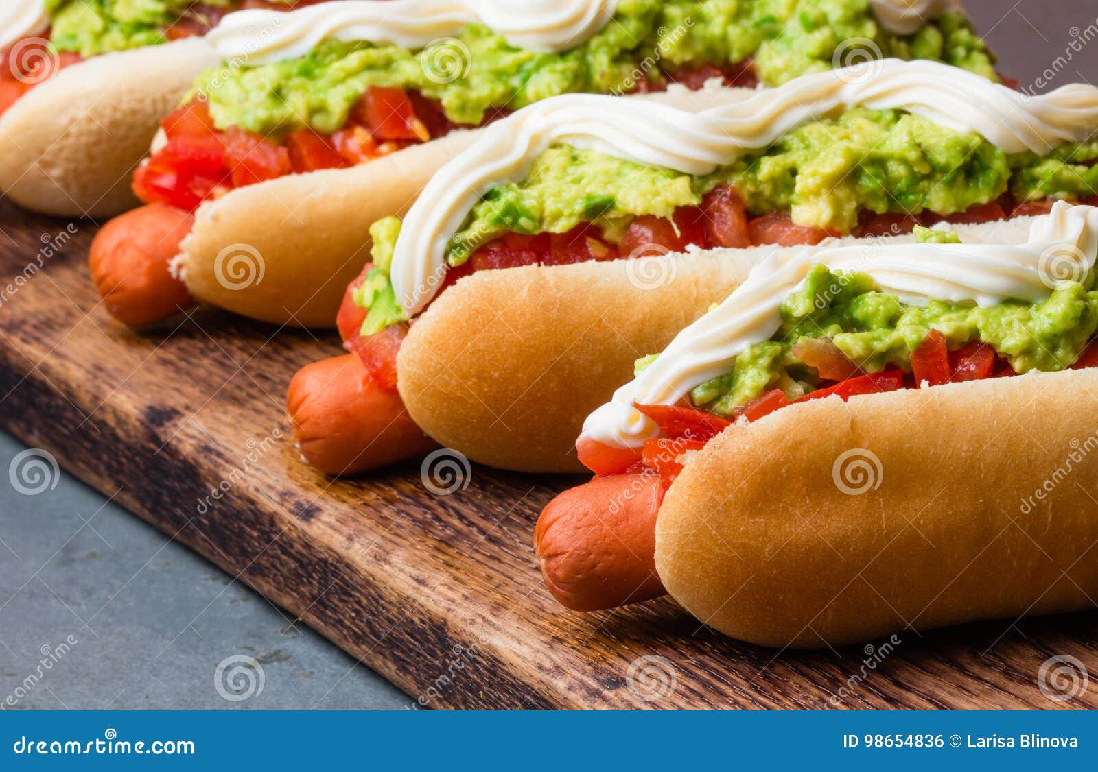 chilean completo italiano. hot dog sandwiches with tomato, avocado and mayonnaise on wooden board. closeup