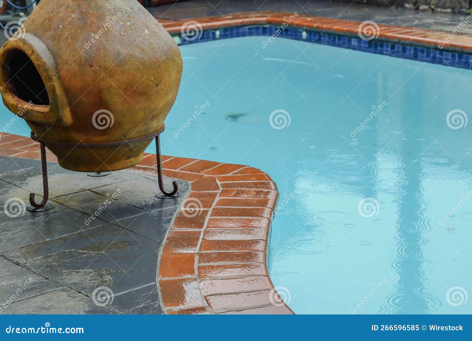 chimenea next to the pool full of clear water on the rainy weather day on blurred background