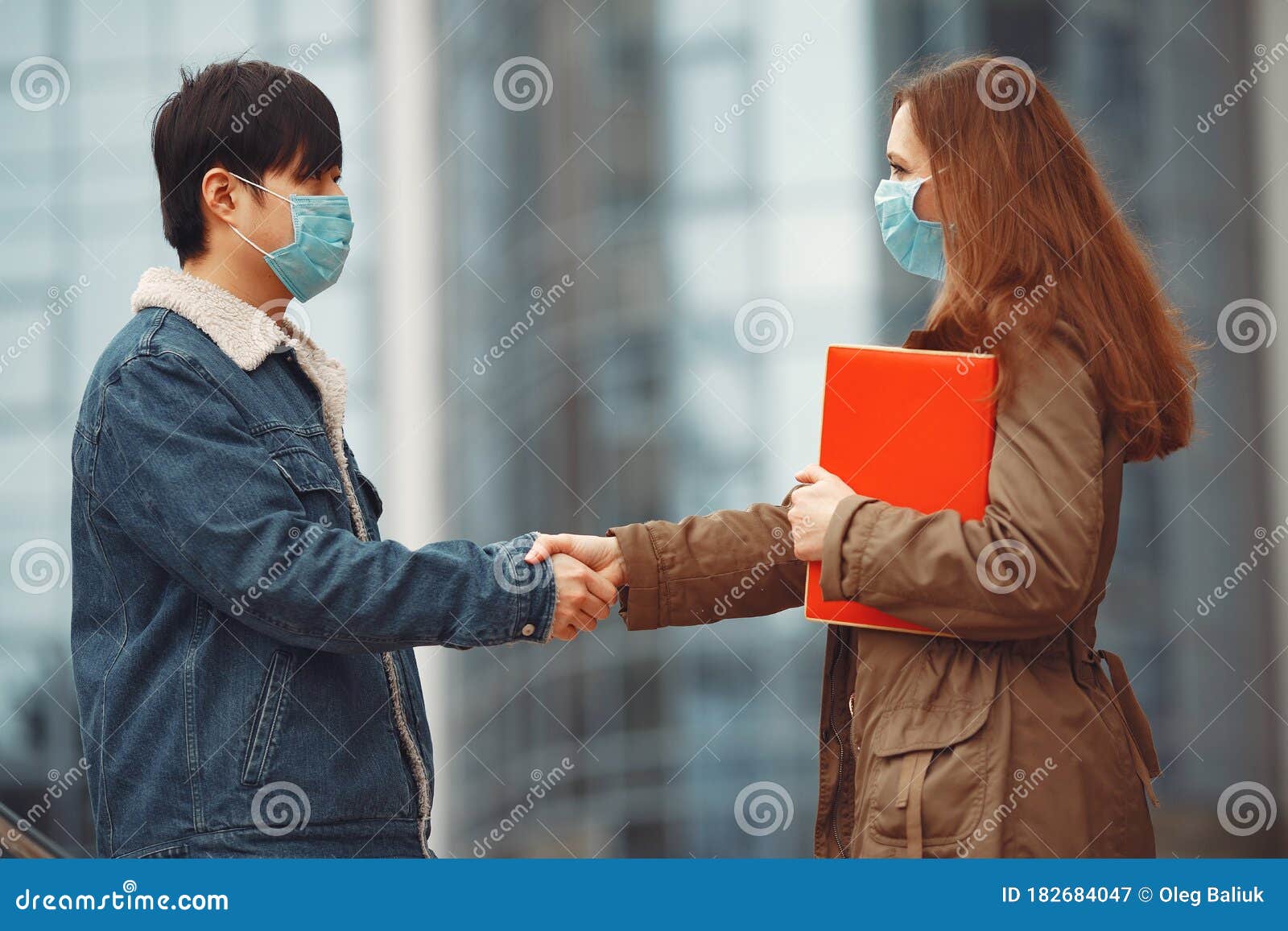 chinese man and a woman in disposable masks are shaking hands