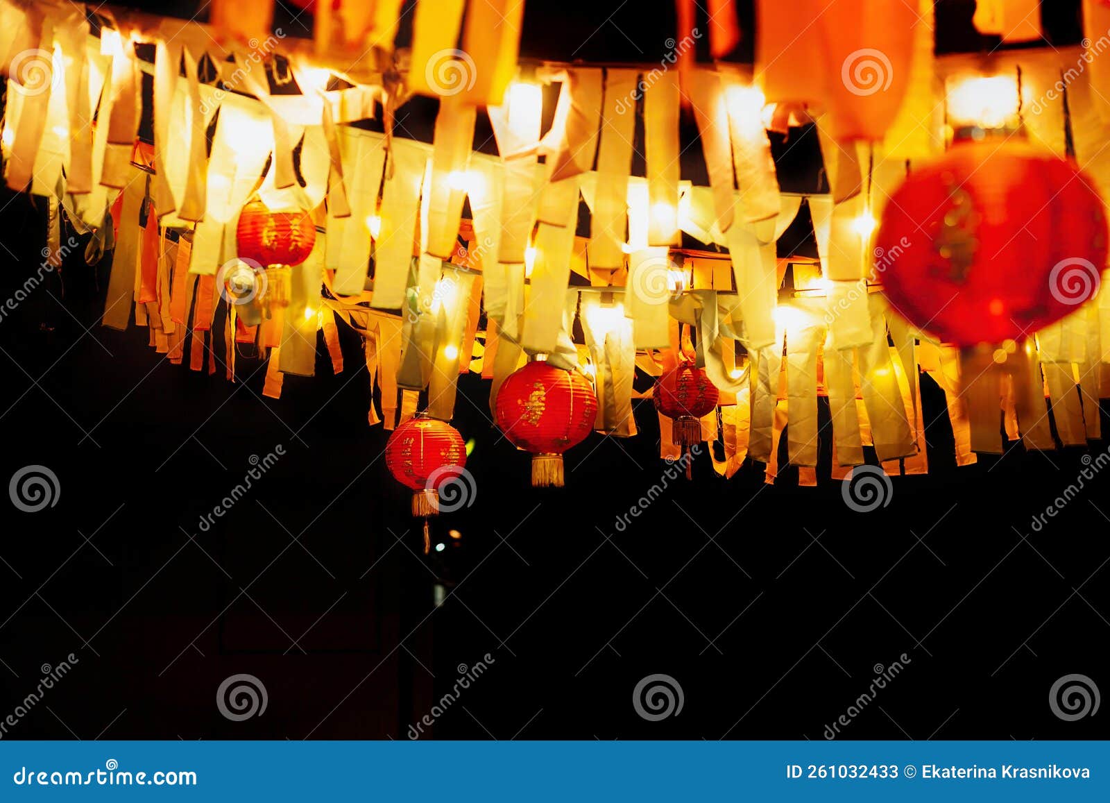 chinese paper red lanterns hang with garlands of ribbons and lamps at night in the yard