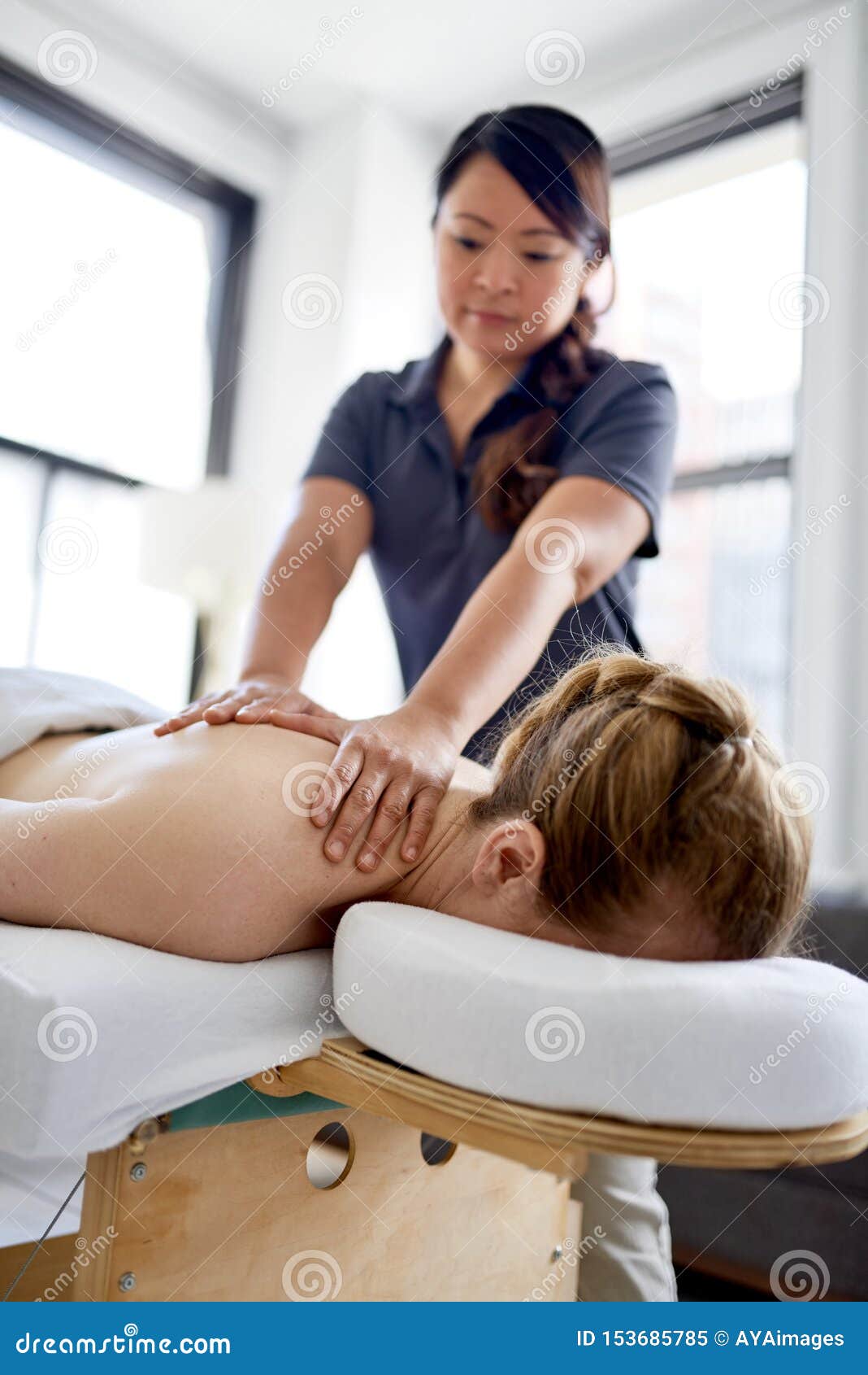 Chinese Woman Massage Therapist Giving A Treatment To An Attractive