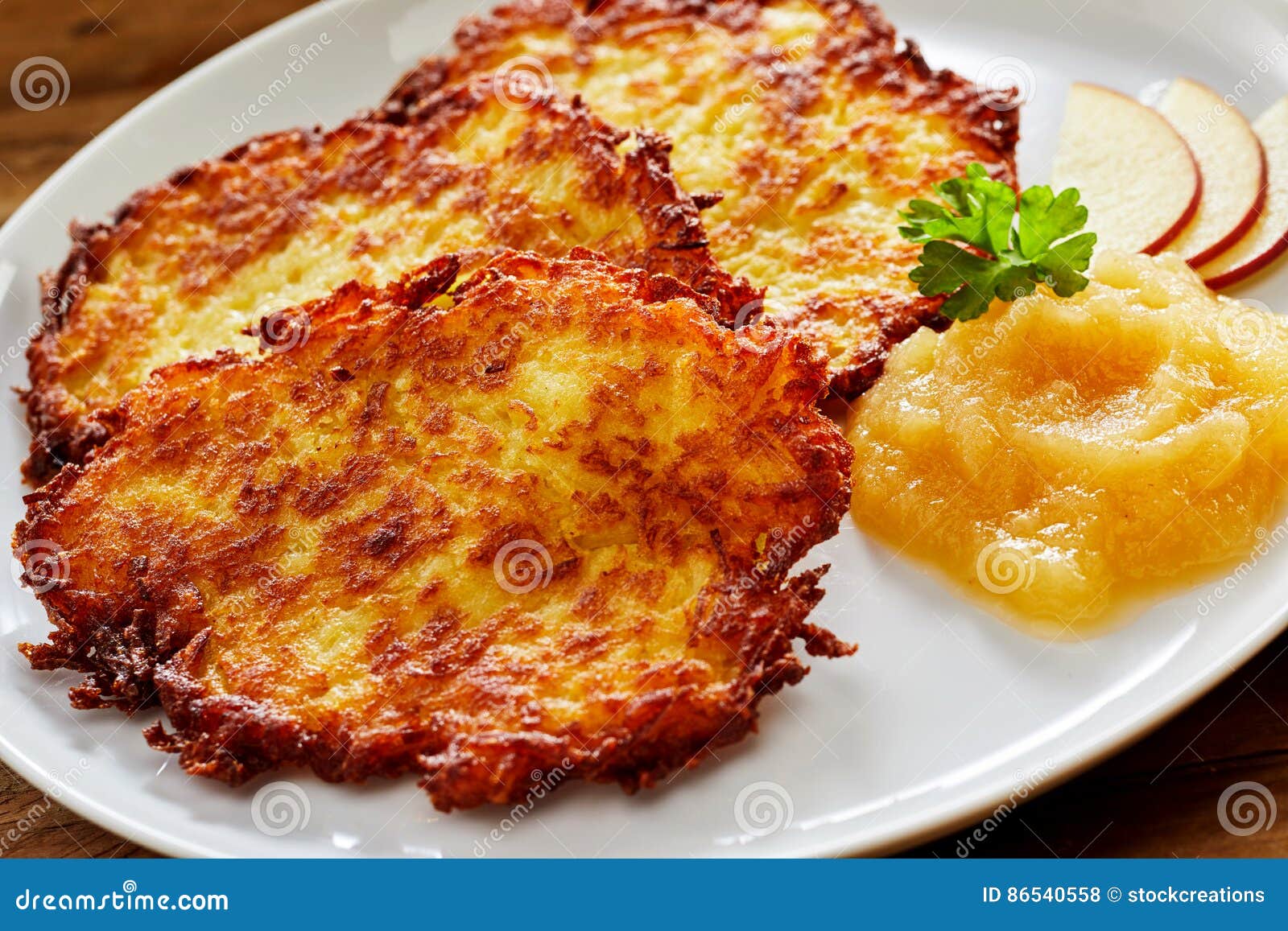 Chips Smażący Kartoflany Rosti Słuzyć z Applesauce. Zamyka W górę Spokojnego życia chipsy Smażący Kartoflani Rosti paszteciki Słuzyć na Nowożytnym bielu talerzu z Pureed Applesauce i Garniruje na stronie