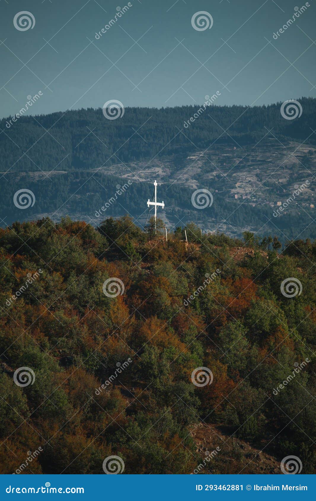 a chistian white cross on top of a mountain.
