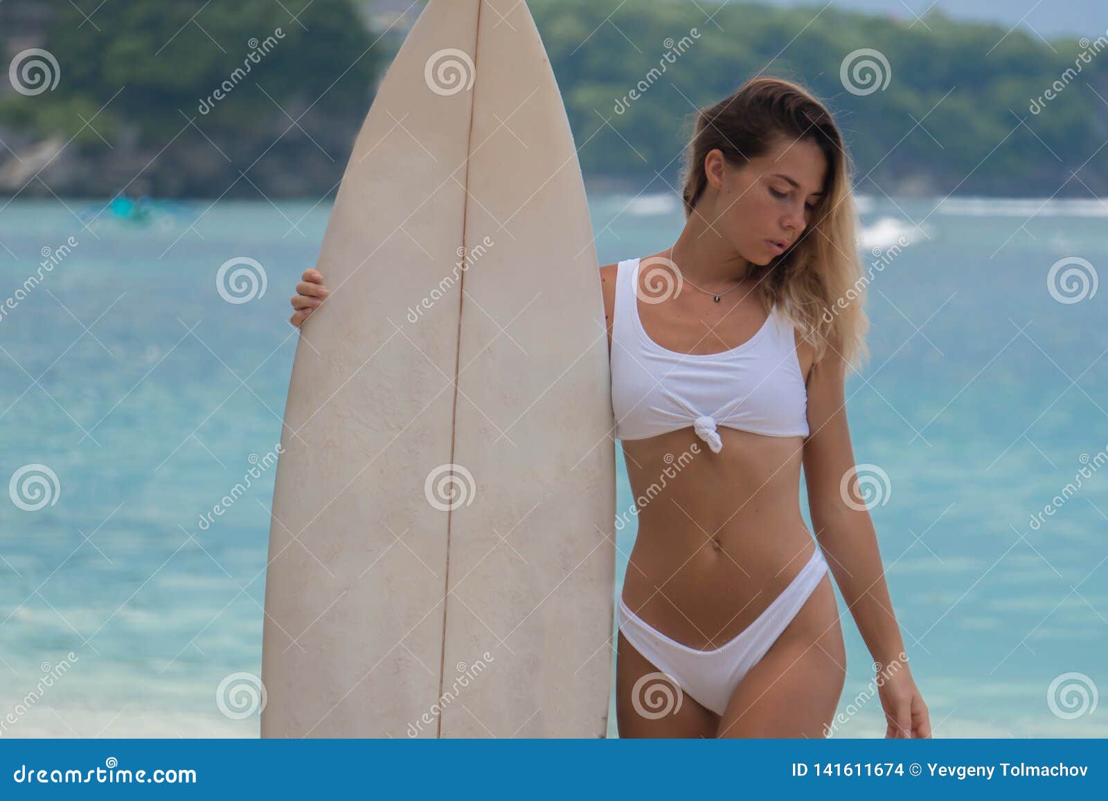 Chiuda su della ragazza snella del bikini sentono il bordo di spuma contro fondo dell'oceano. Chiuda su della ragazza snella del bikini sentono il bordo di spuma contro fondo di acqua profonda dell'oceano con la costa folta, la vacanza tropicale, il giorno soleggiato all'aperto