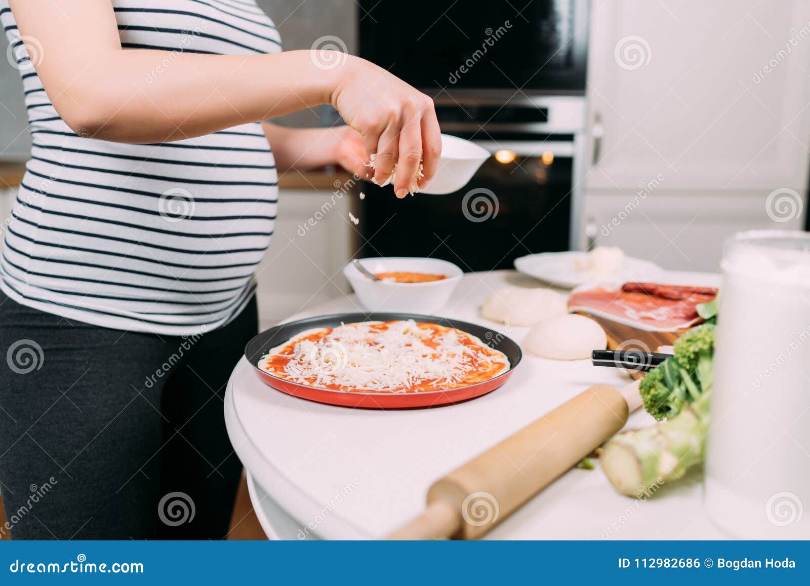 Chiuda sui dettagli della donna incinta che producono la pizza domestica. Dettagli della donna incinta che producono pizza domestica