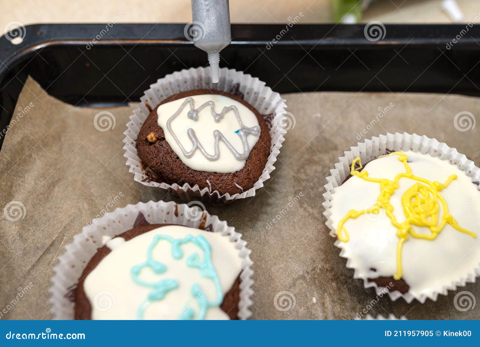 chocolate brown muffins wrapped in white paper and covered with white frosting with colorful decorations, baked in the oven, lying