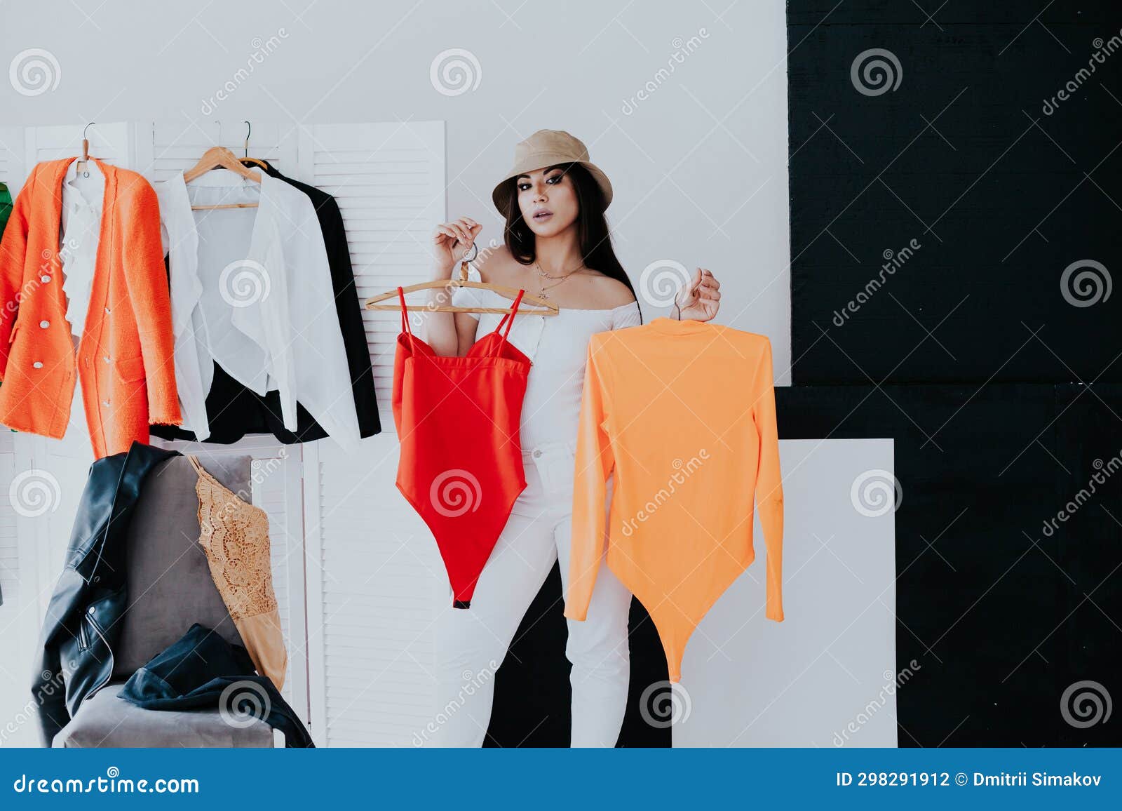 Choice of clothes,Nothing to wear. Attractive asian young woman, girl  looking into mirror, try on appare, choosing dress, outfit on hanger in  wardrobe at home. Deciding blouse what to put on which